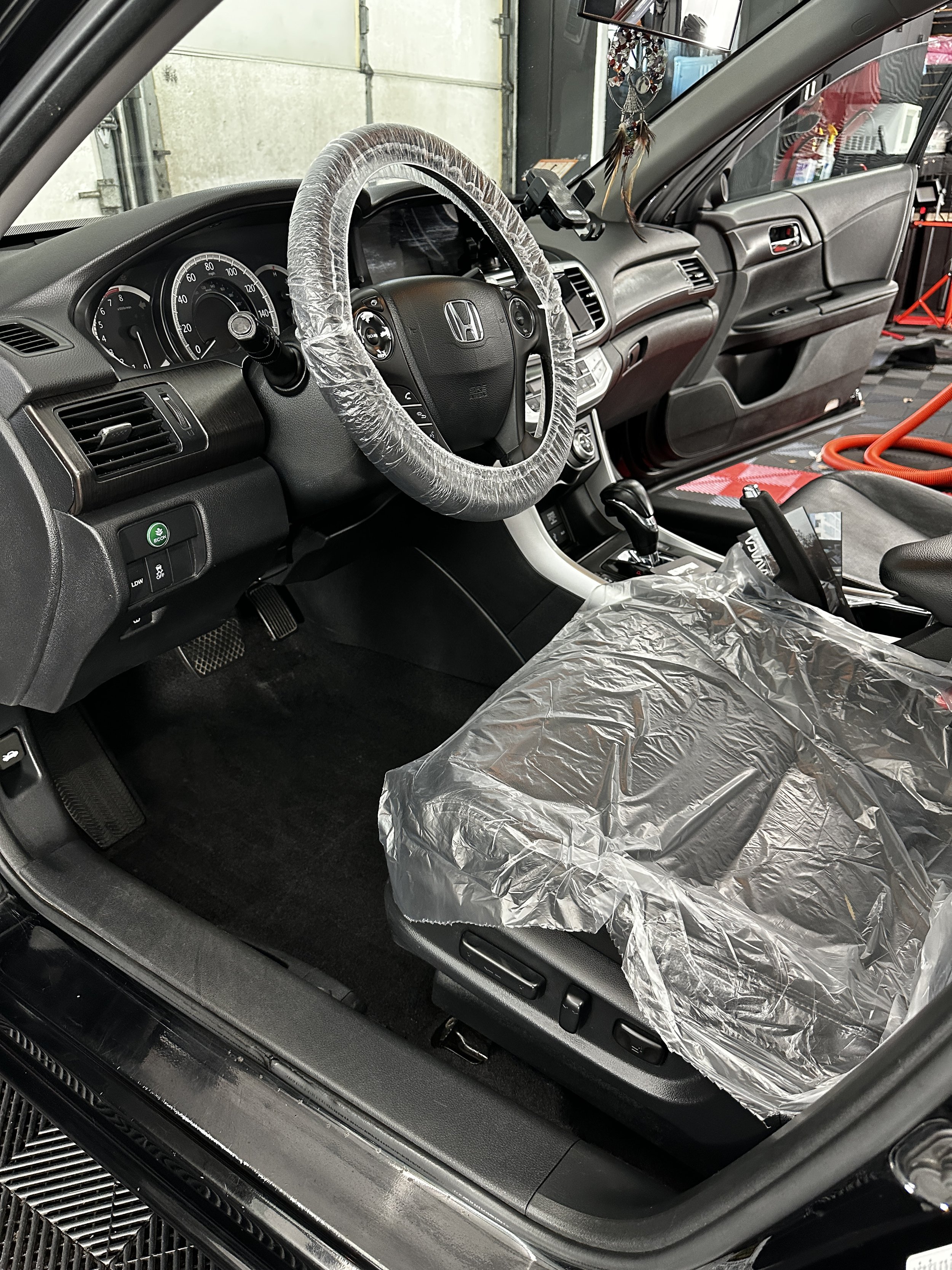 Steering wheel and seat covered in plastic before an interior detail