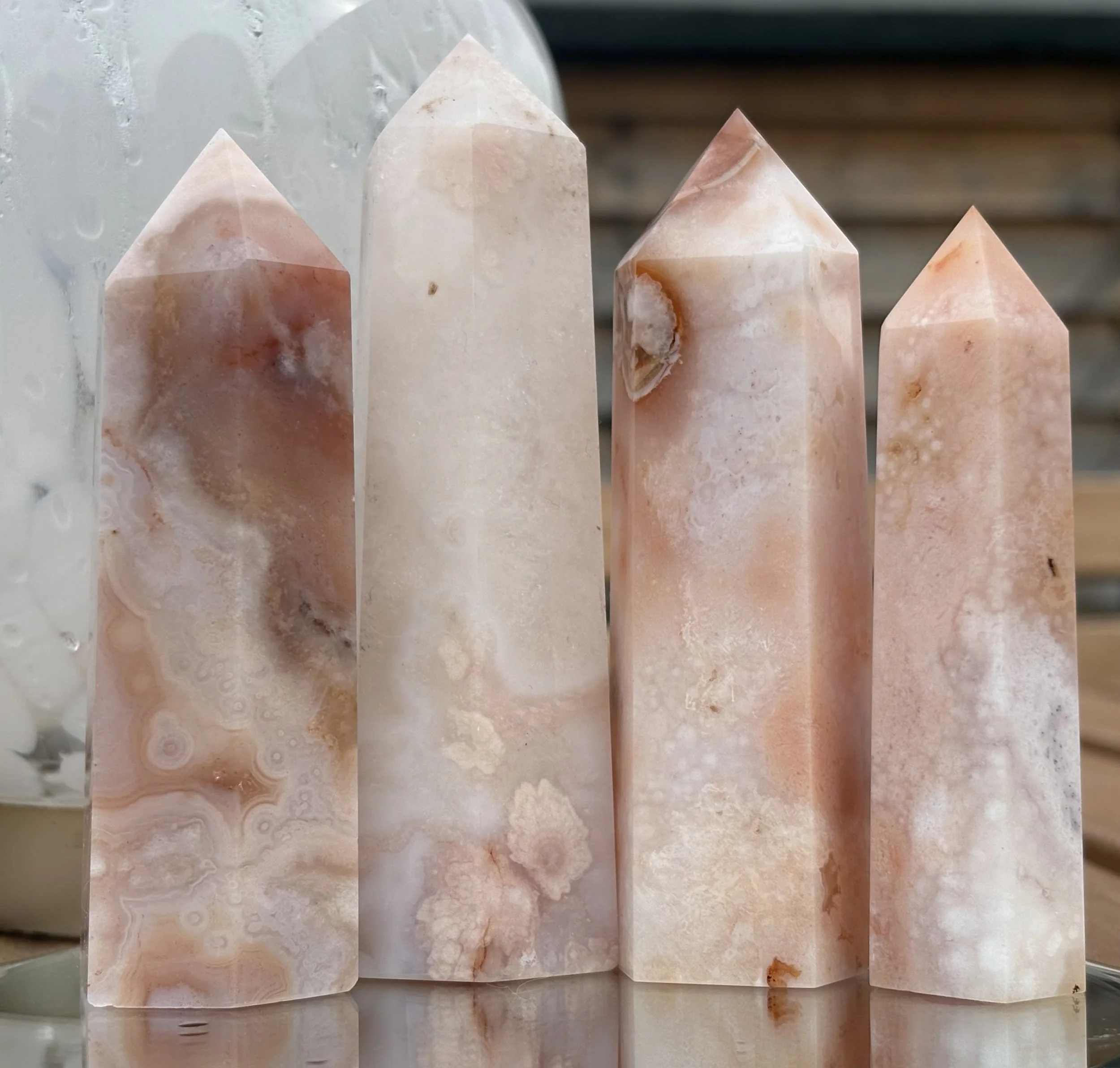 A row of five pink and white marble obelisks with pointed tops, positioned on a reflective surface.