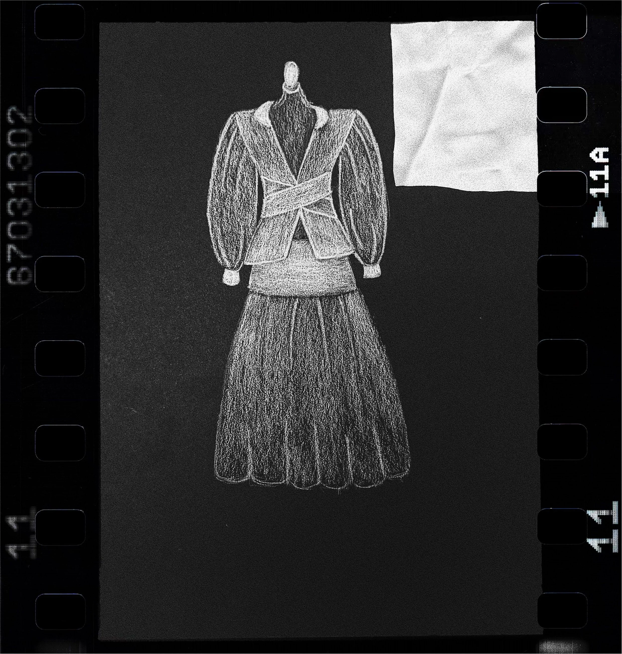 A digital camera screen showing a chalk drawing of a woman in a blazer and skirt with her arms crossed, standing against a split background of black and white.