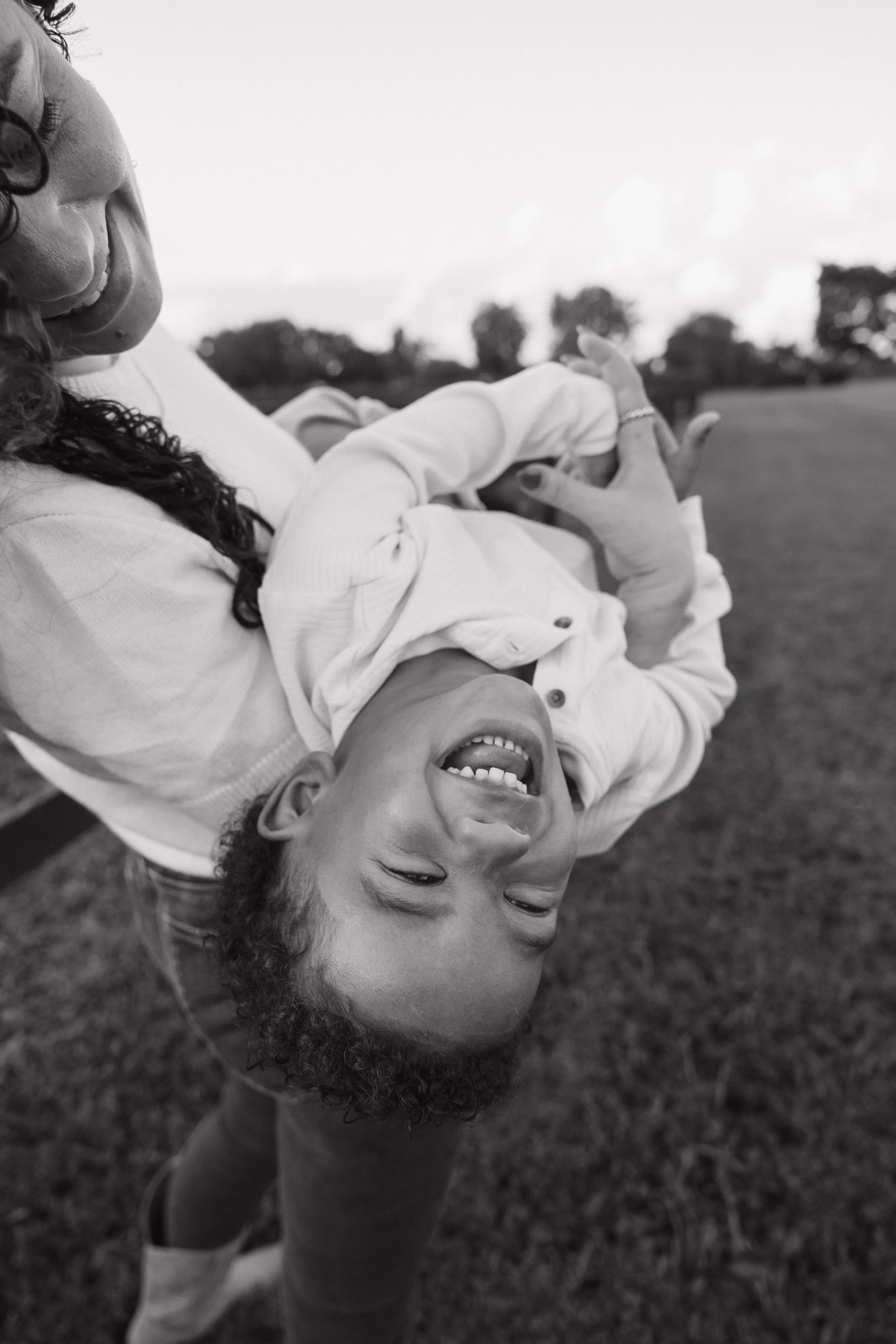 A woman and boy playing and laughing outdoors, seen from a low-angle black-and-white photograph.