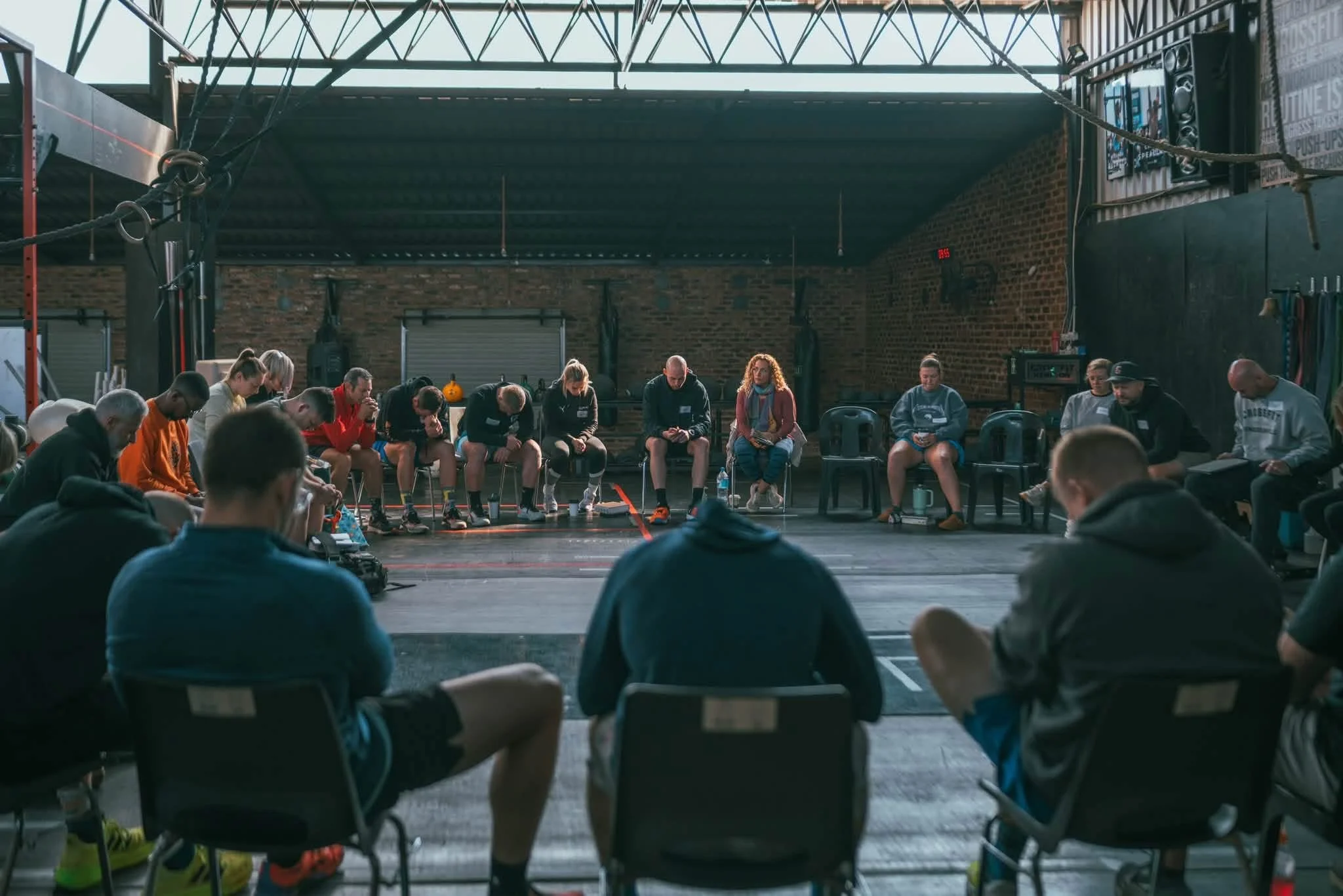 Group of people sitting in a circle in a gym, participating in a group activity or meeting.