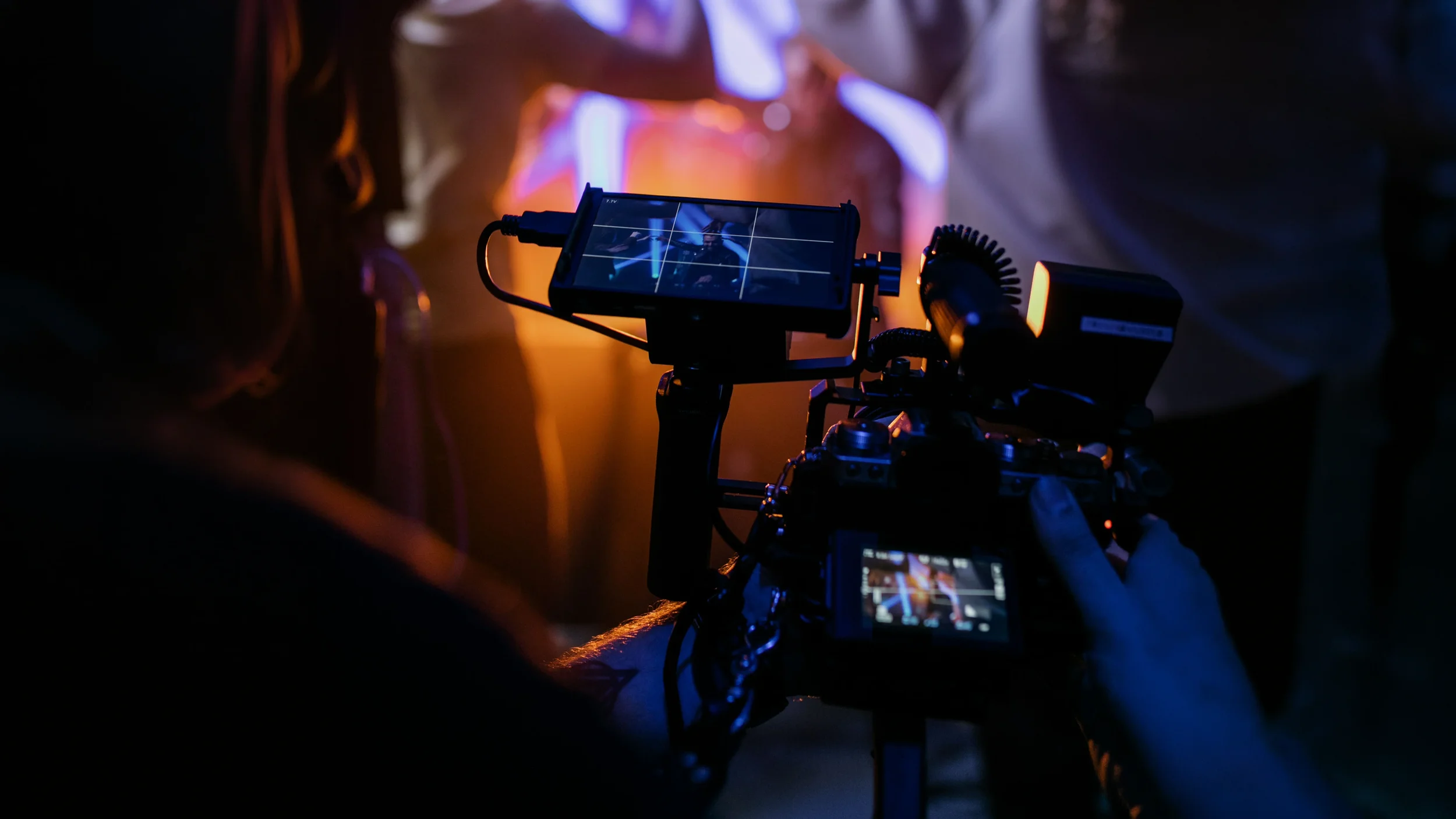 A camera operator filming a scene with colorful lighting effects.