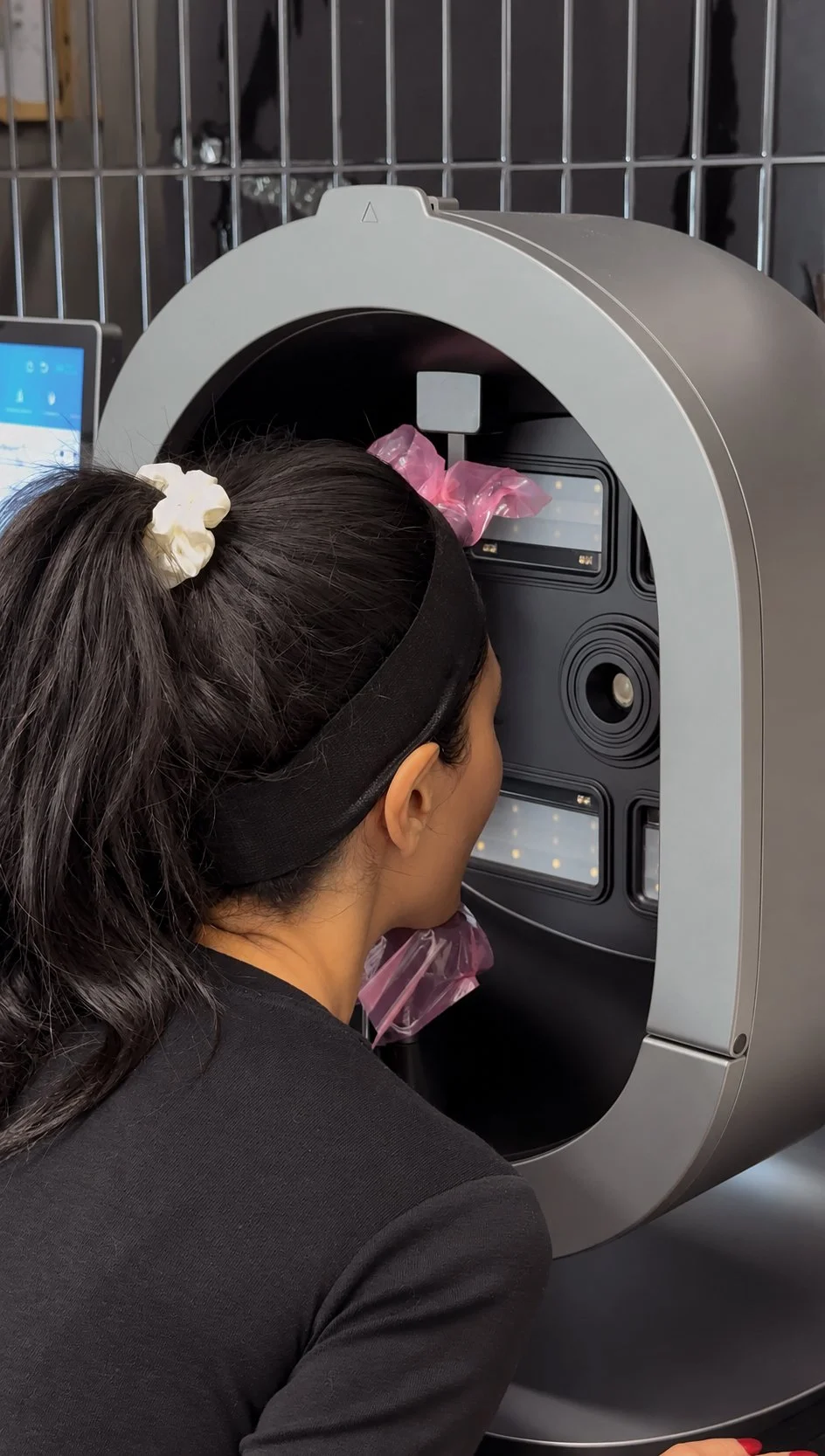 Woman wearing a headband undergoing a facial scan in a large imaging device