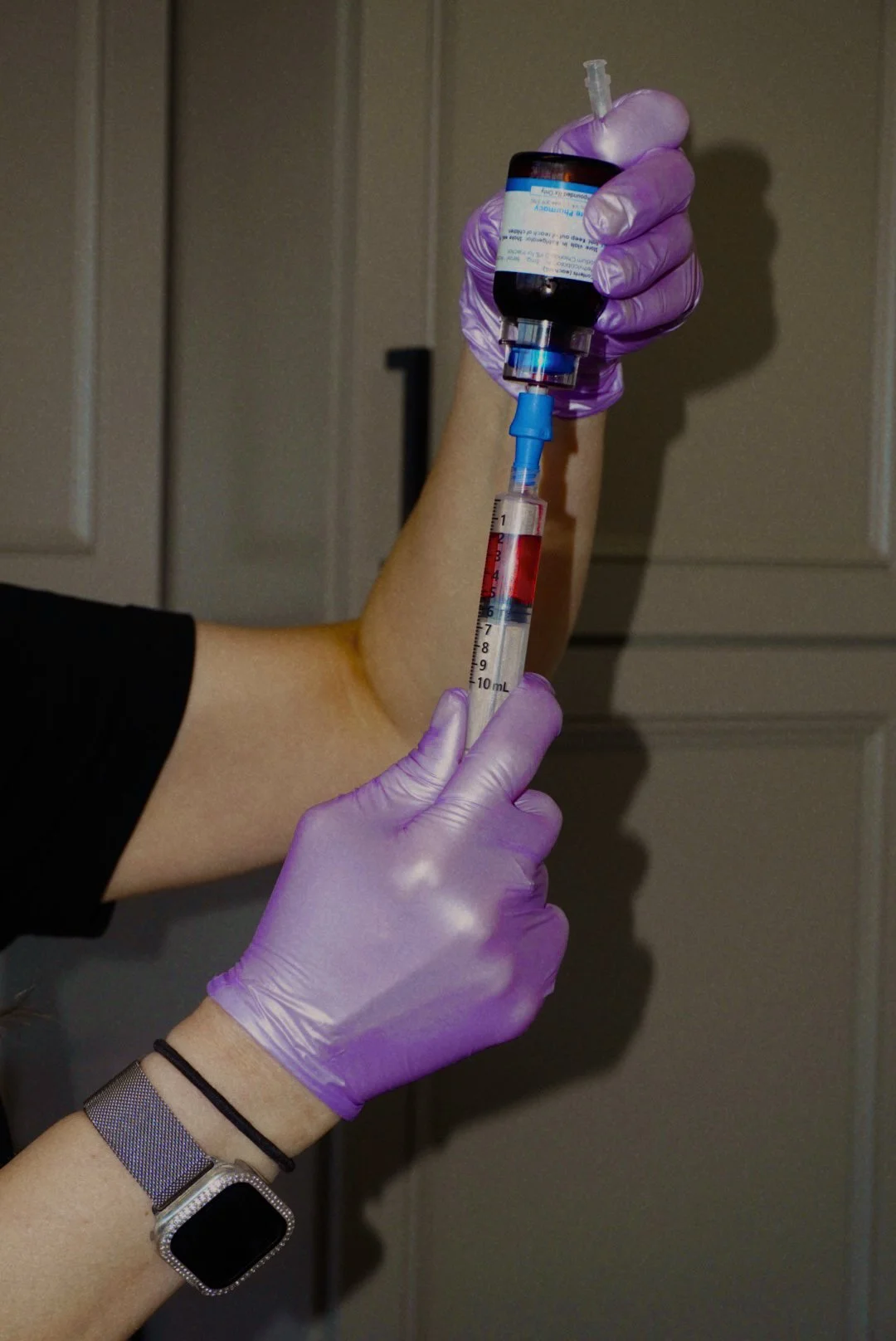 Gloved healthcare worker drawing medication from a vial into a syringe
