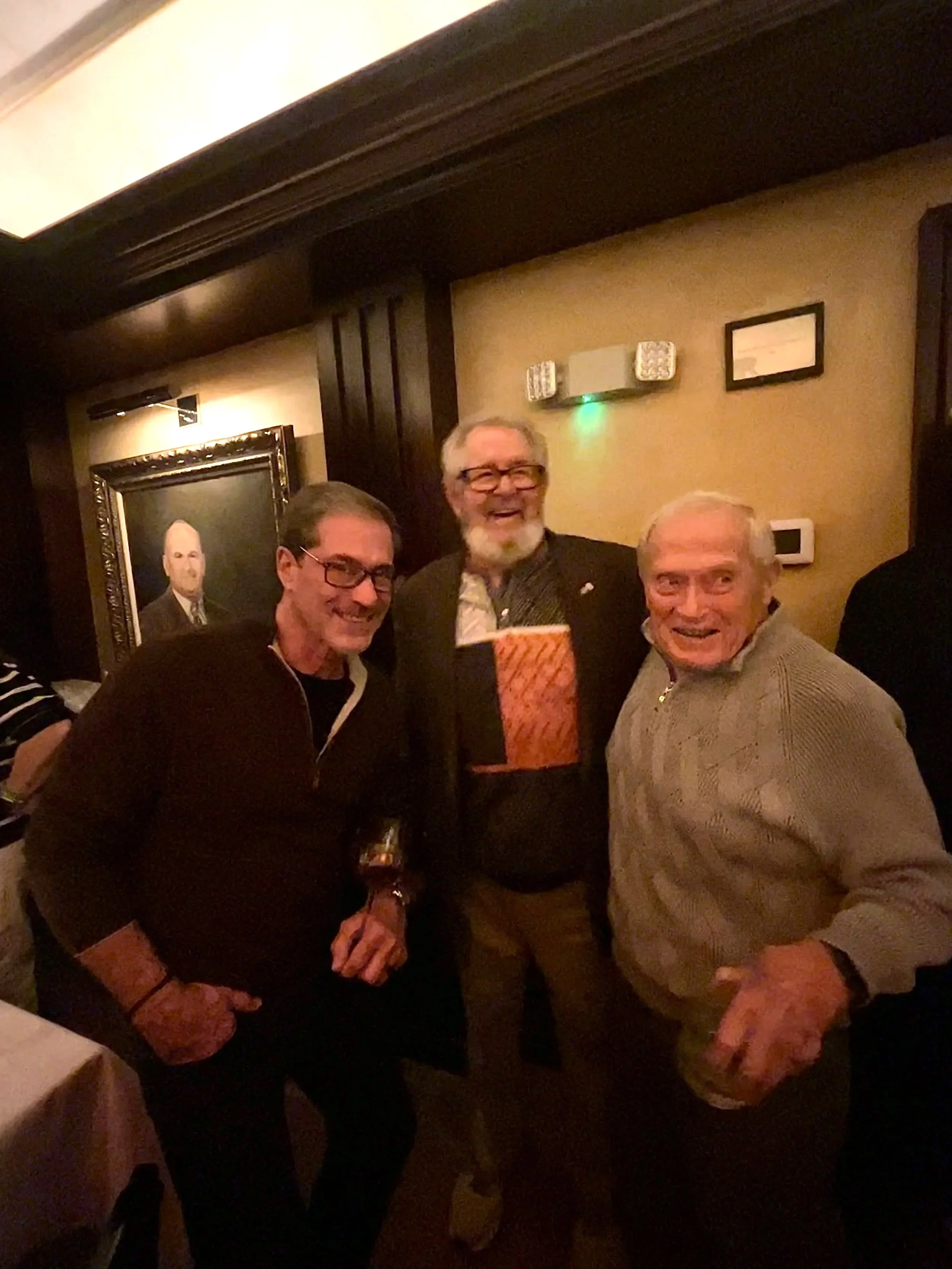 Three adults 50+ socializing together at an indoor gathering.