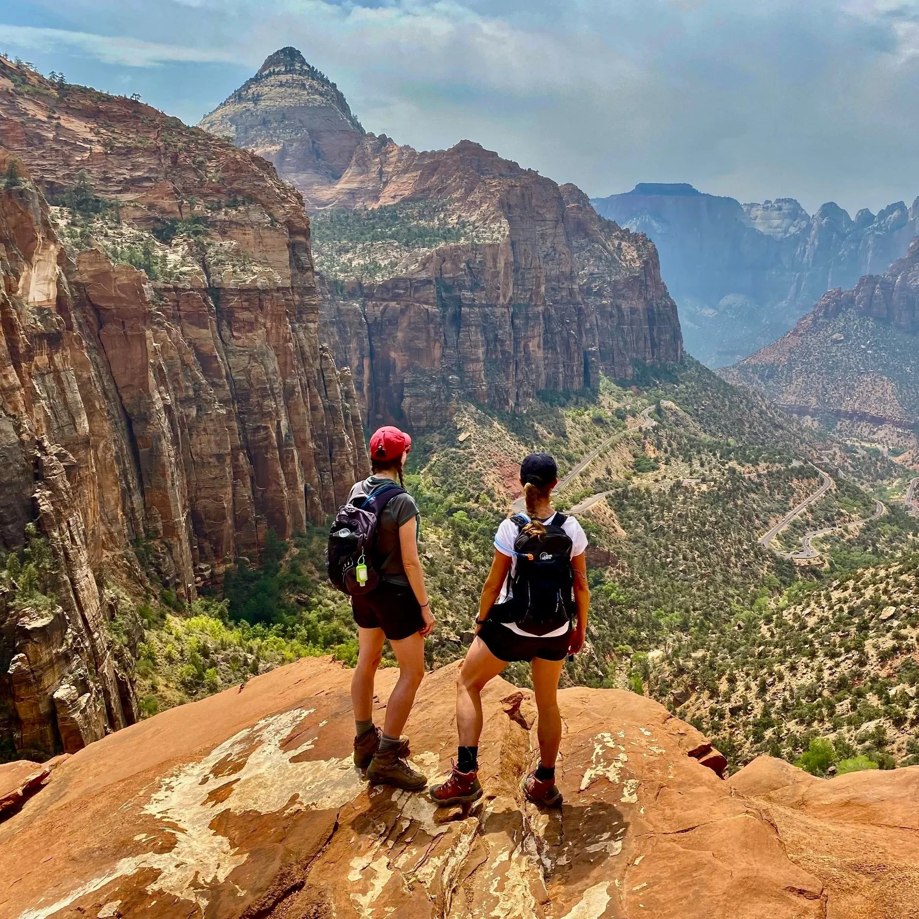 Two adults hiking and overlooking a mountain canyon.