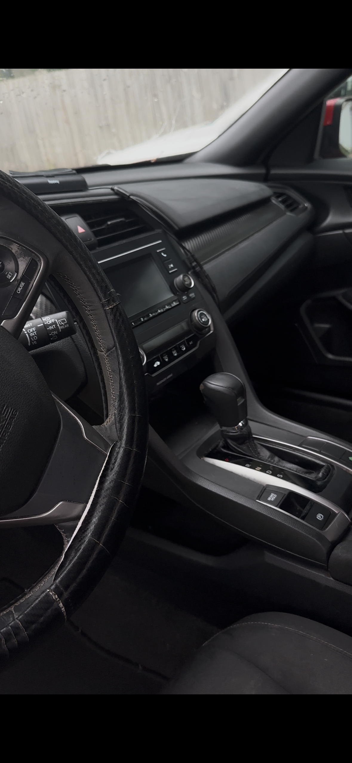 Interior of a car showing the steering wheel, dashboard, gear shift, and front passenger seat.