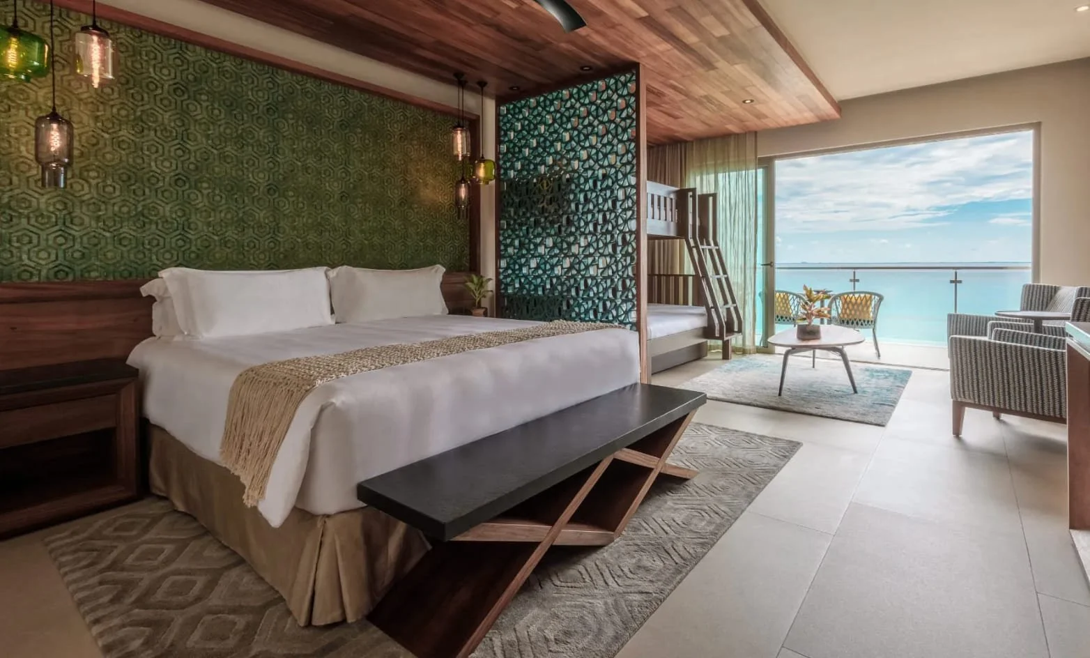 Luxury hotel room with a large bed, a sitting area, and balcony with ocean view.