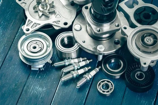 Various automotive engine parts, including pulleys, bearings, and bolts, arranged on a dark wooden surface.