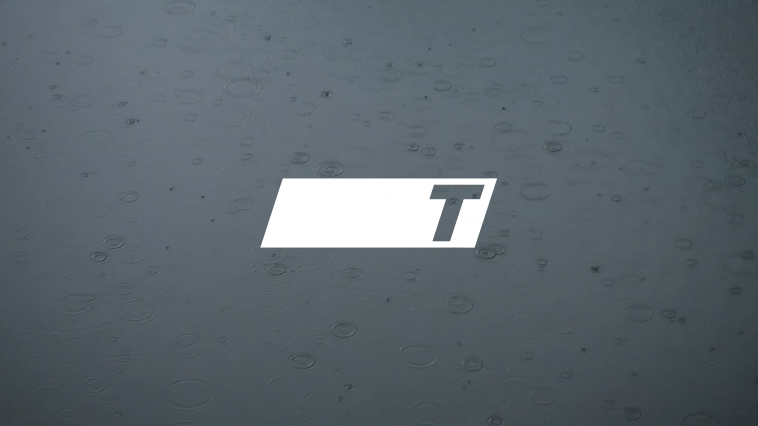 Raindrops on a surface with a white rectangular logo containing a stylized letter 'T'.