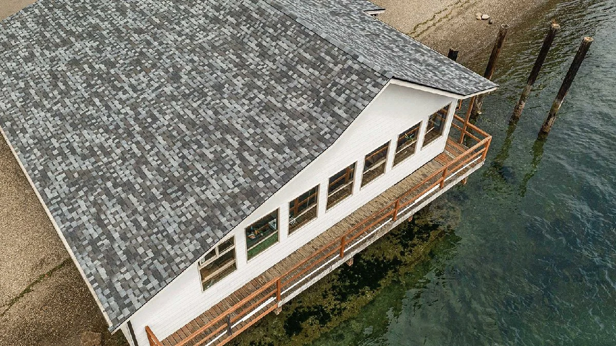 Aerial view of a waterfront building with a newly shingled roof for Valentine Roofing.