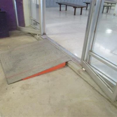 Sliding glass door with a small ramp made of a wooden plank for accessibility.