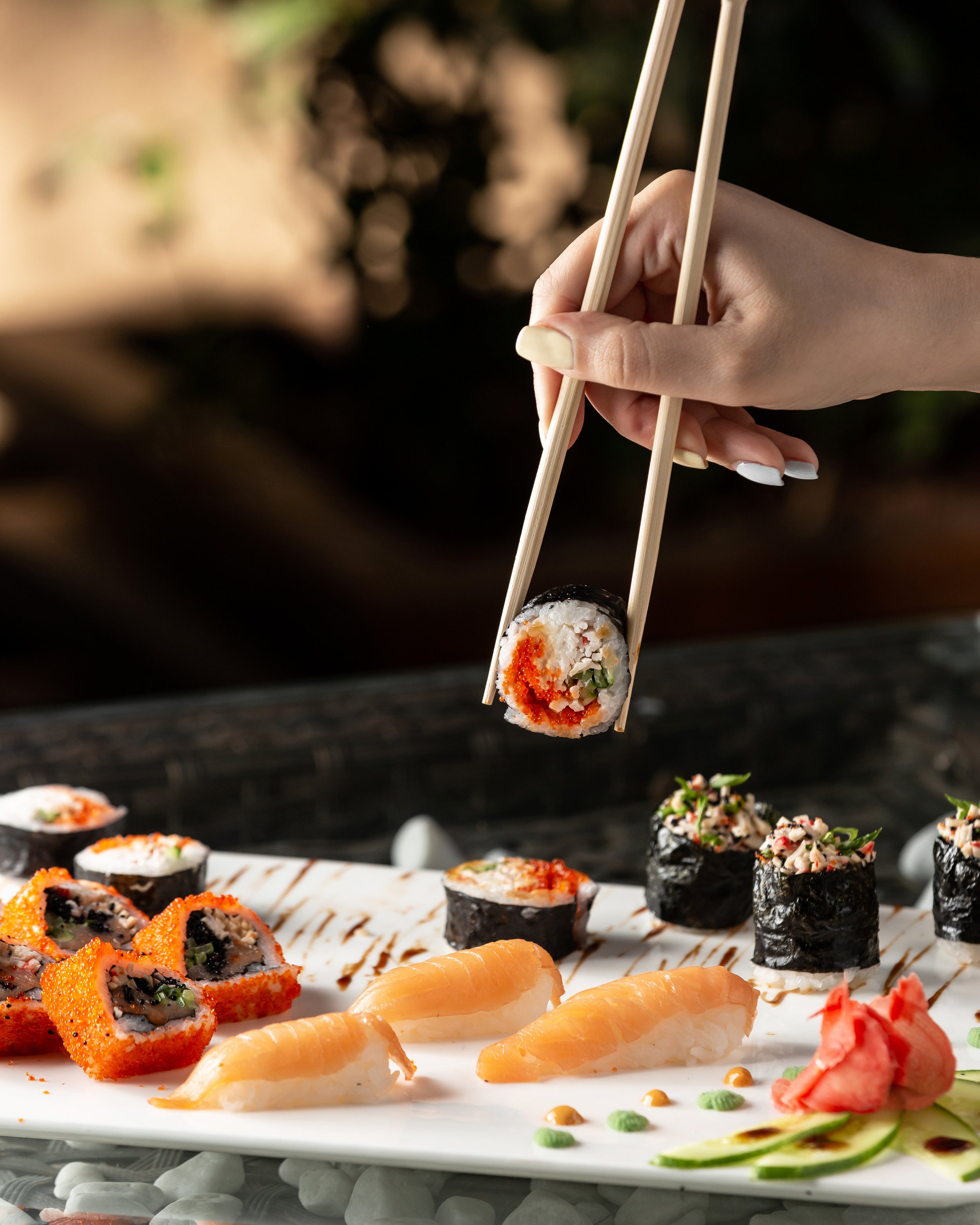 woman-holding-sushi-roll-with-chopsticks.jpg