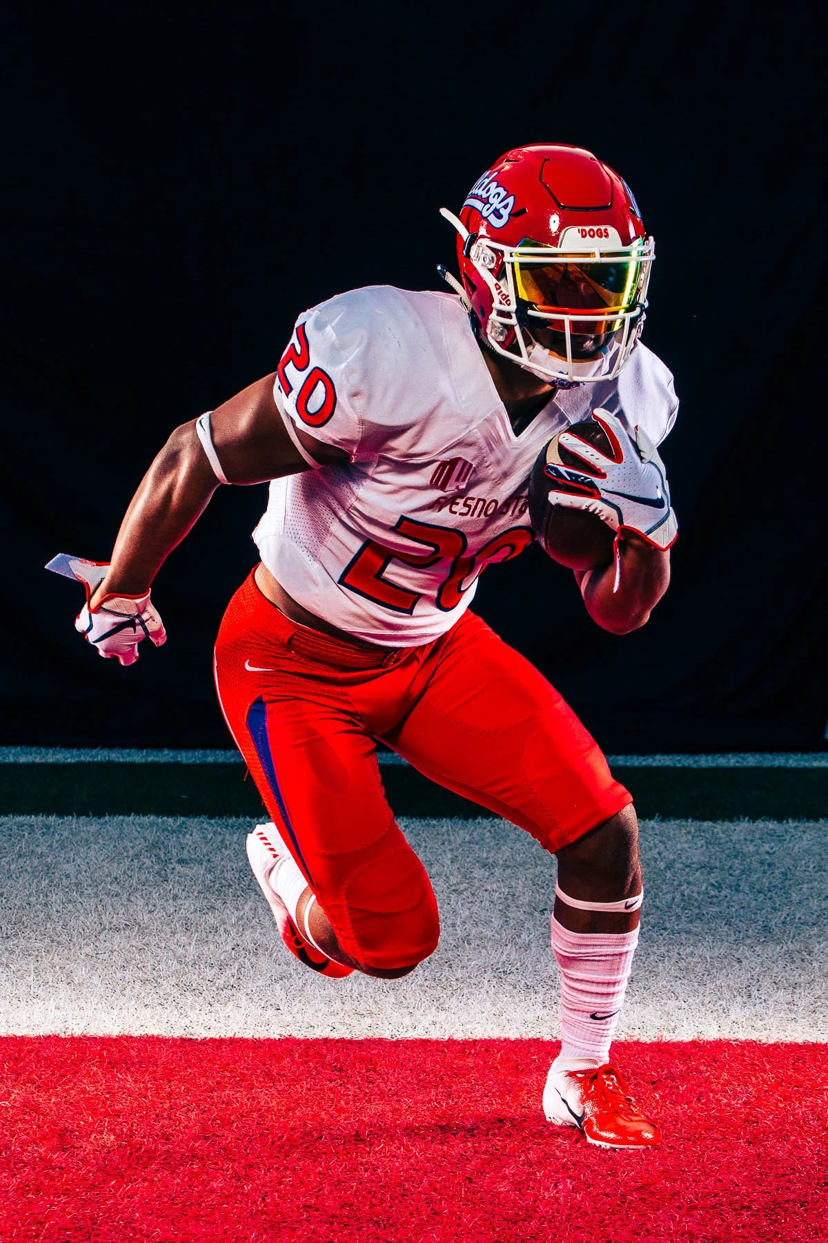 American football player in a white and red uniform running with the ball on a football field.