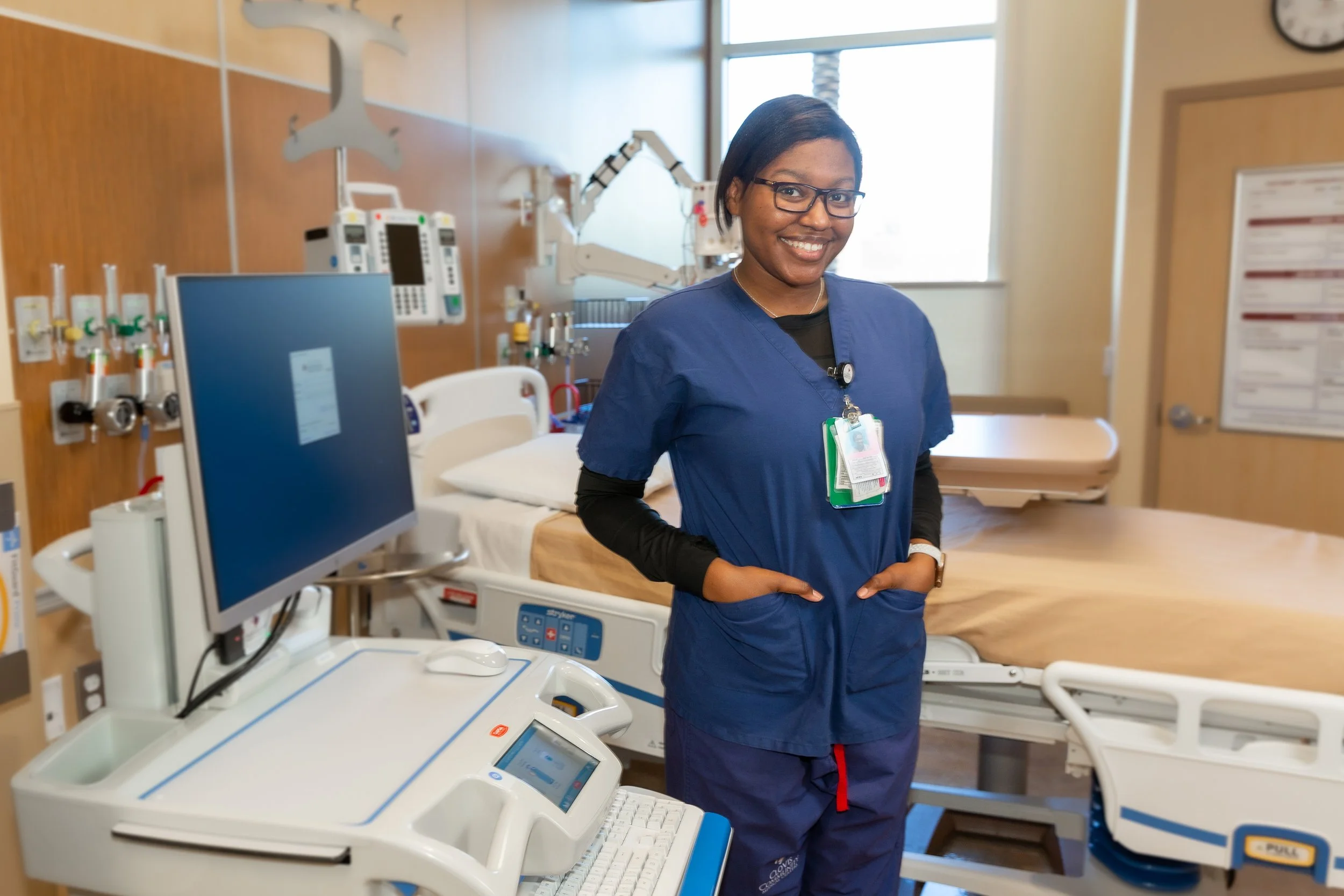A nurse standing in a hospital room with medical equipment and a hospital bed.