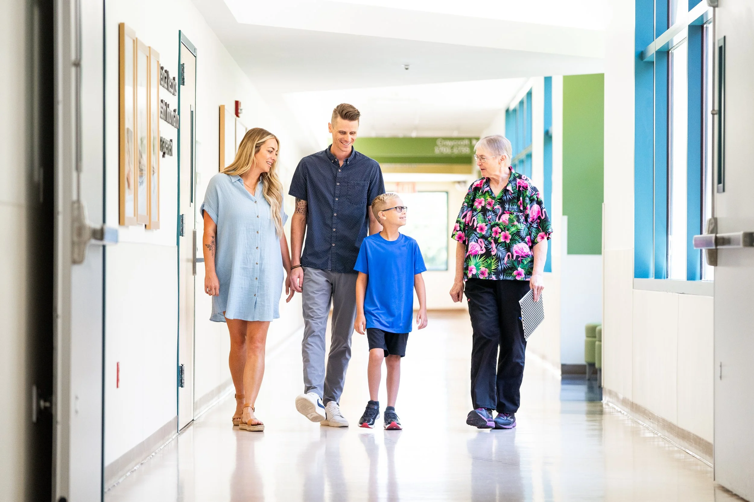 Family of four walking down a hospital corridor, smiling and talking.