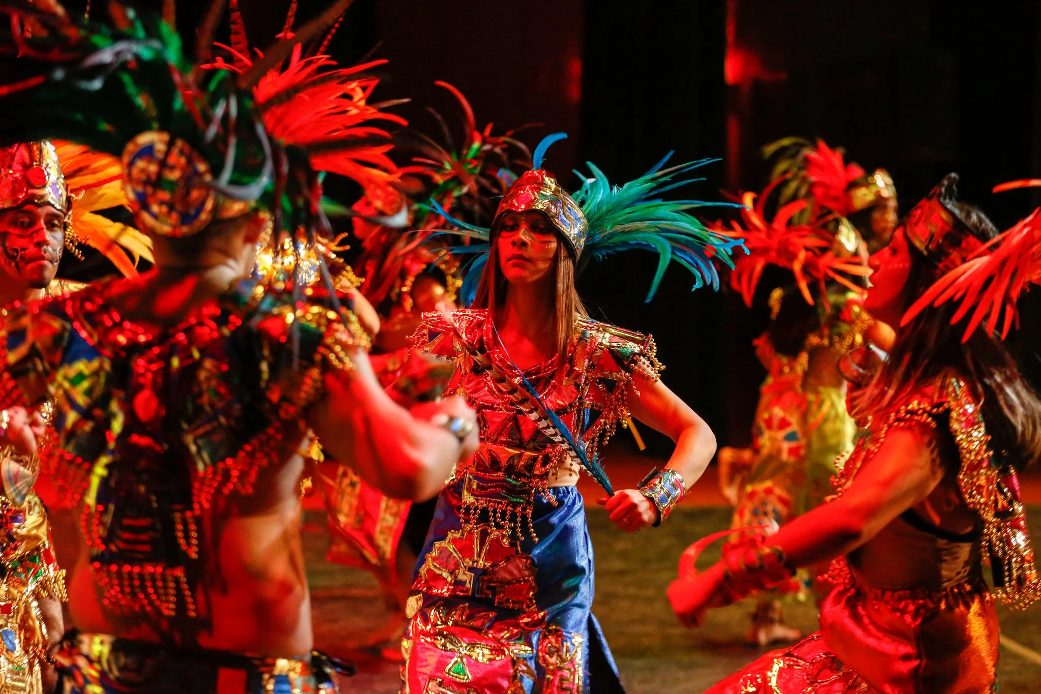 People participating in a traditional dance or celebration, wearing colorful costumes and feathered headdresses.