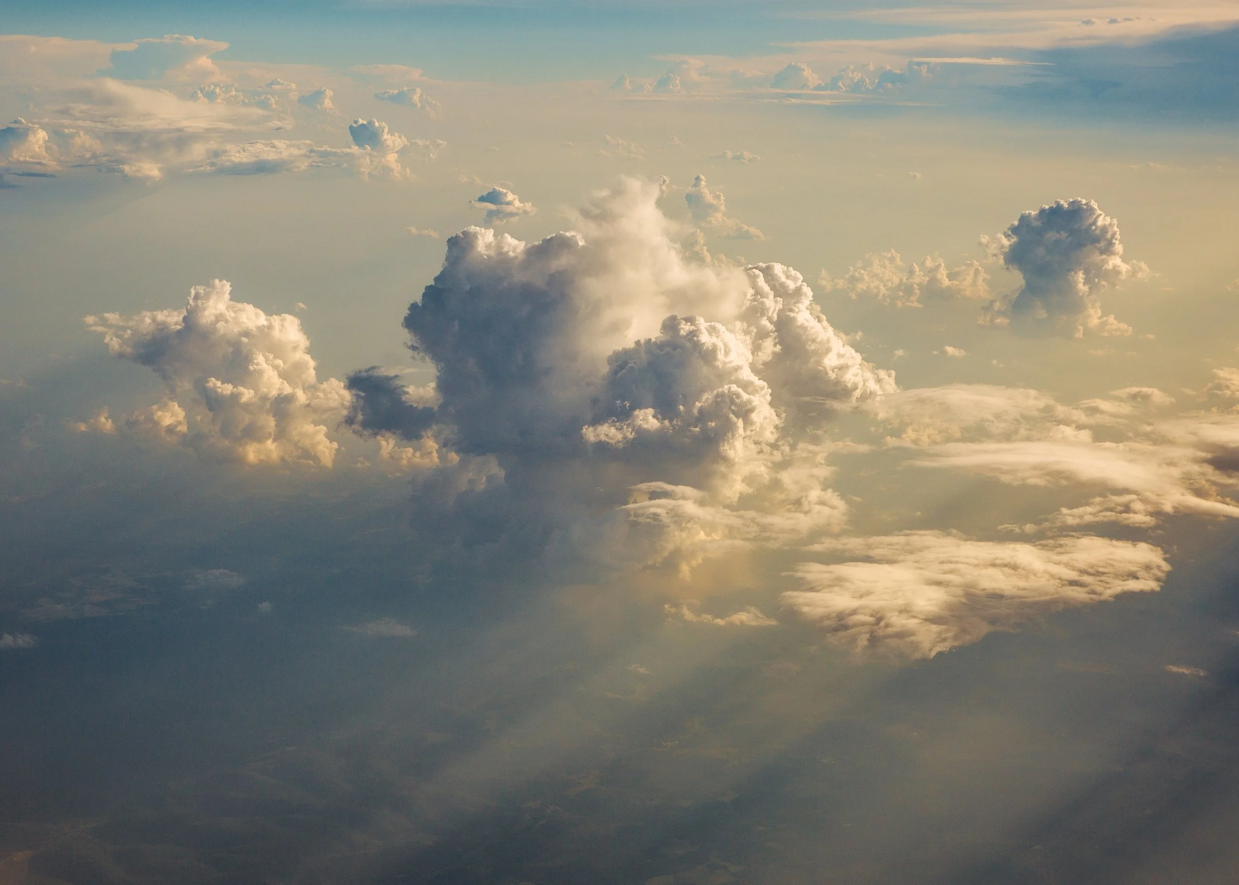 Sky filled with various clouds at different altitudes, with sunlight illuminating some clouds and creating a serene atmosphere.