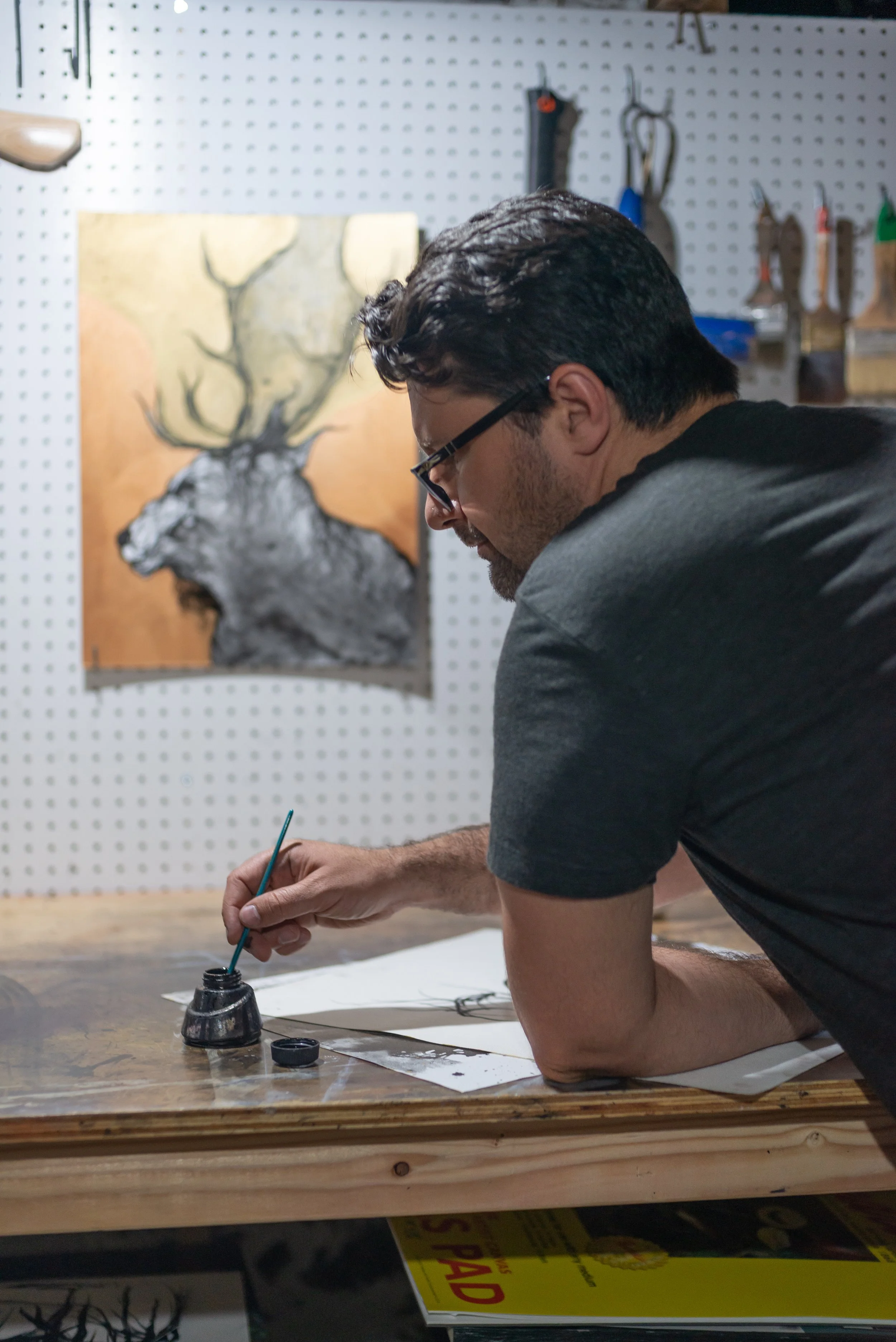 Daniel Abramovici, founder of Form & Wonder, painting on a large sheet of paper in his art studio.