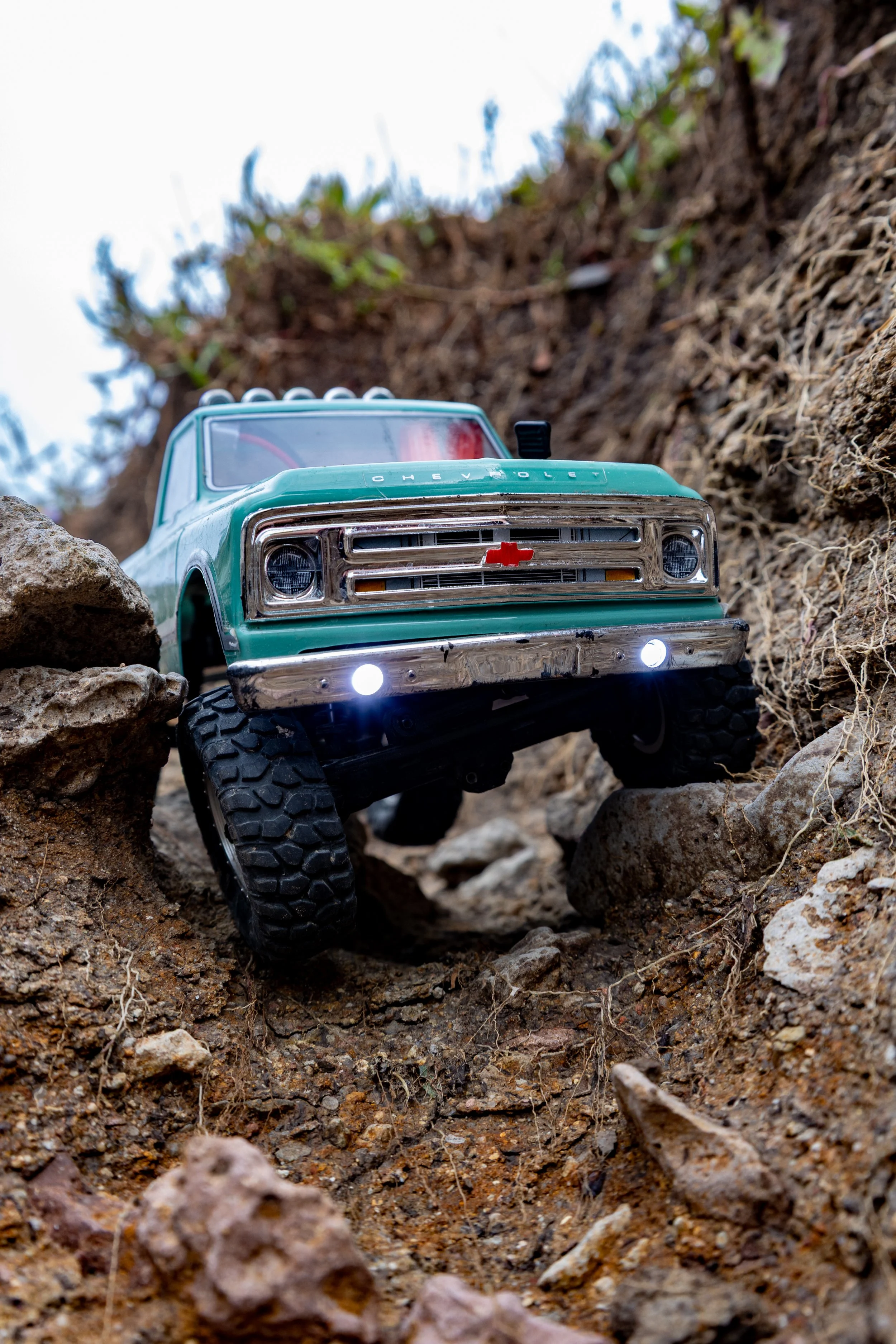A small toy Chevrolet truck navigating rocky terrain outdoors 