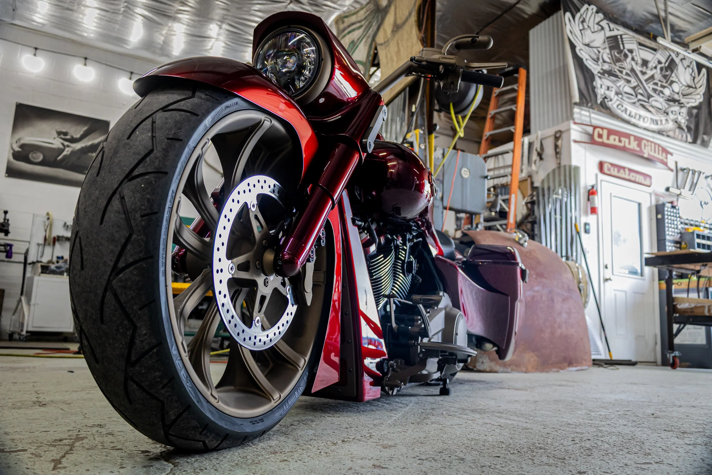 Red motorcycle in a workshop with tools, a ladder, and graffiti on the walls.