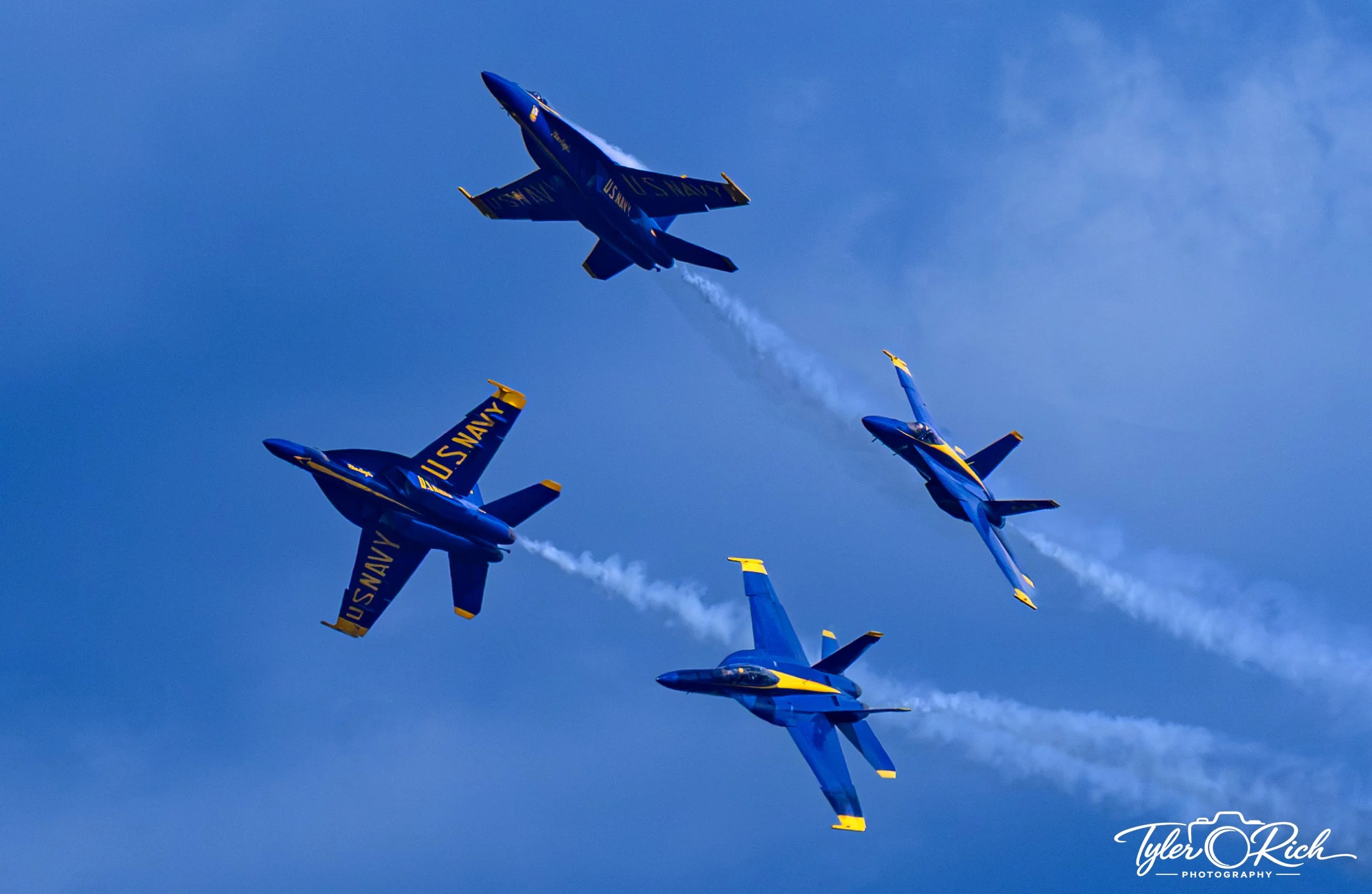 Fighter jets flying in close formation against a blue sky, with the text 'U.S. NAVY' visible on the wings.