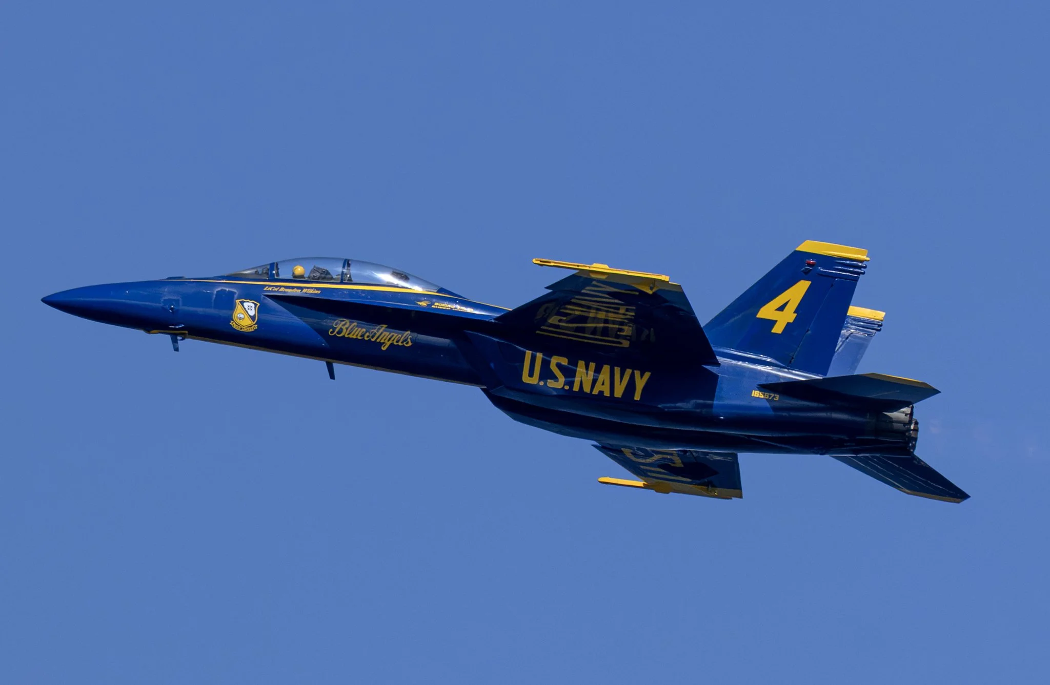 U.S. Navy Blue Angels jet photographed in flight against a clear blue sky.