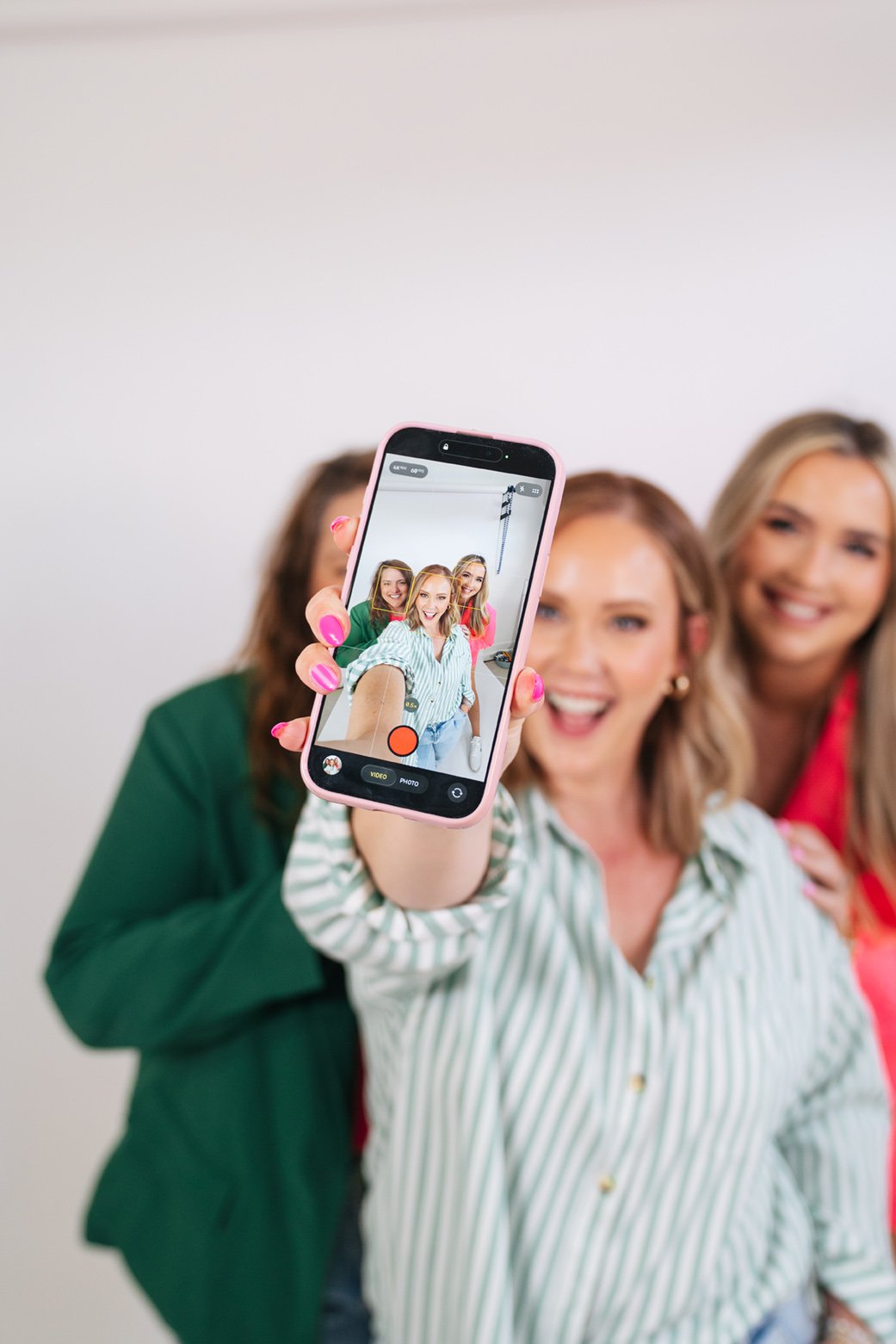 Woman holding up a phone recording video of the Birch & Bloom team, with all three on the screen