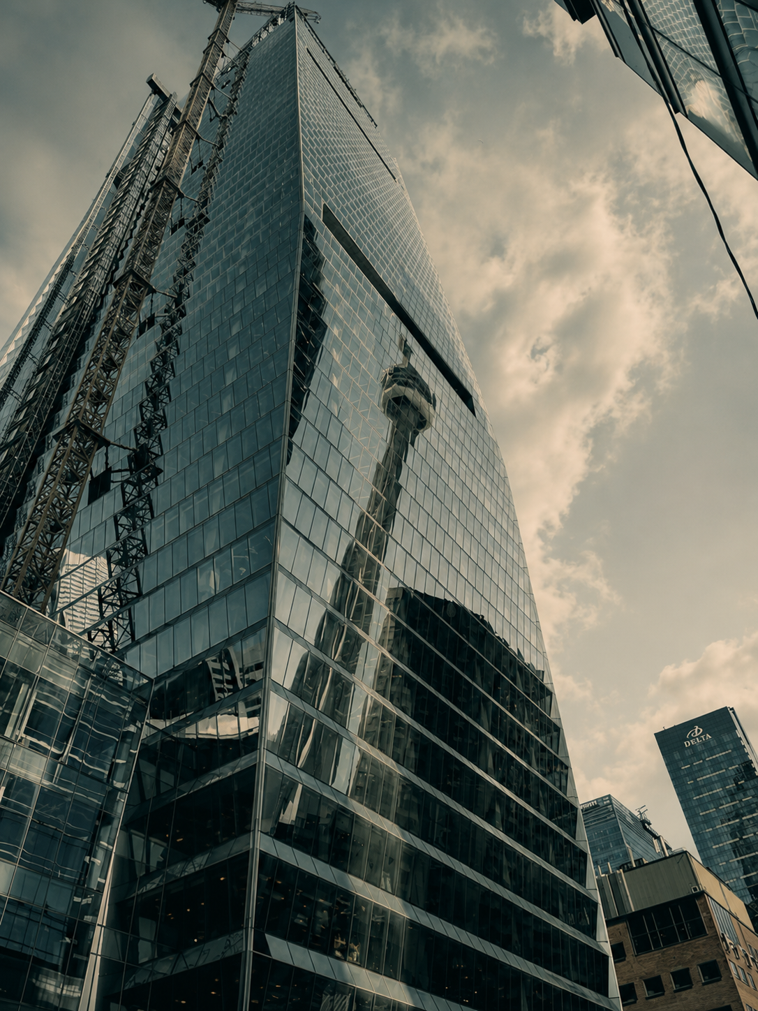 A glass skyscraper reflecting the Space Needle and the surrounding cityscape in downtown Seattle on a cloudy day.