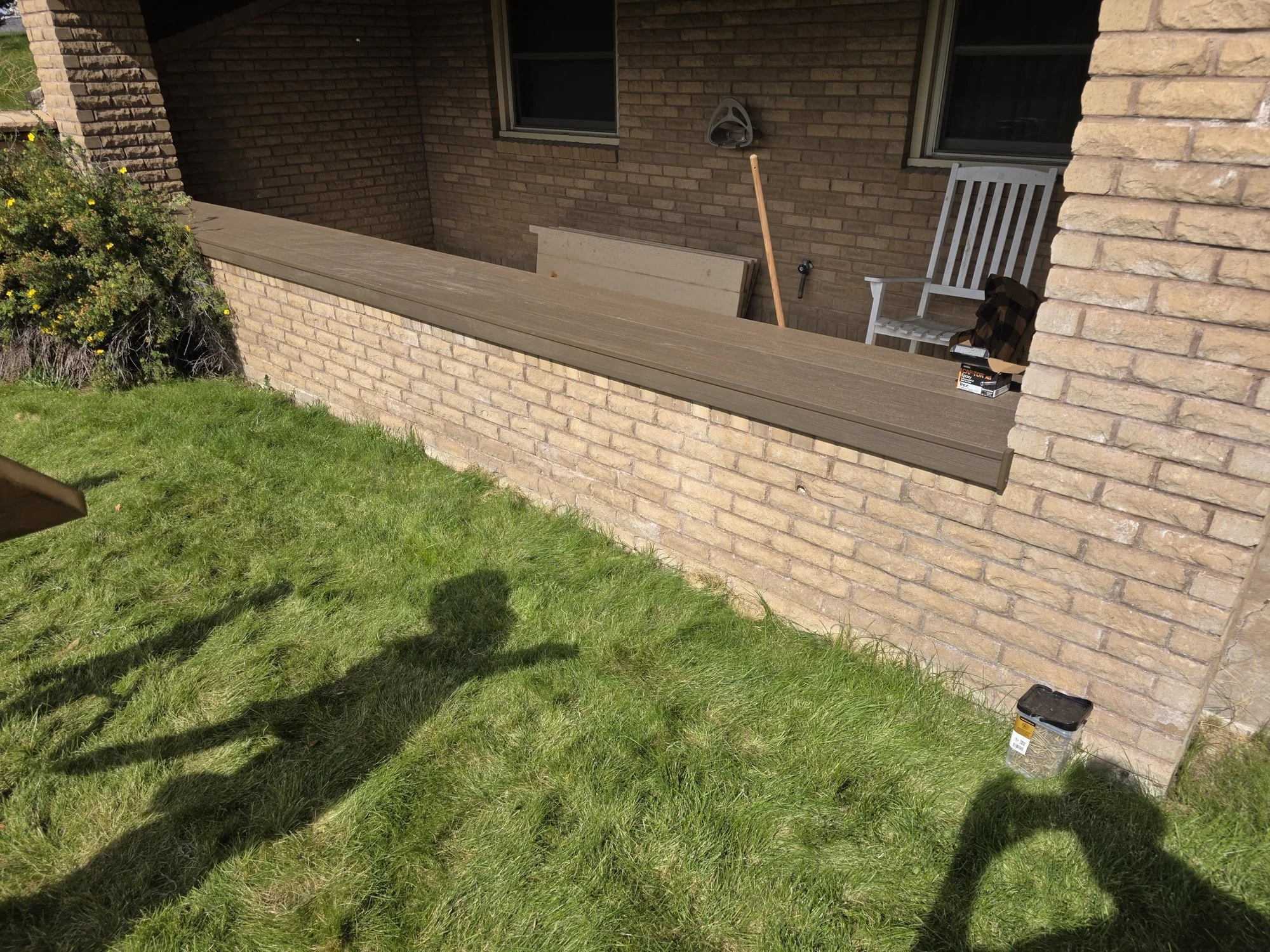 Finished composite decking cap on a brick planter wall along the front of a Butte, Montana home