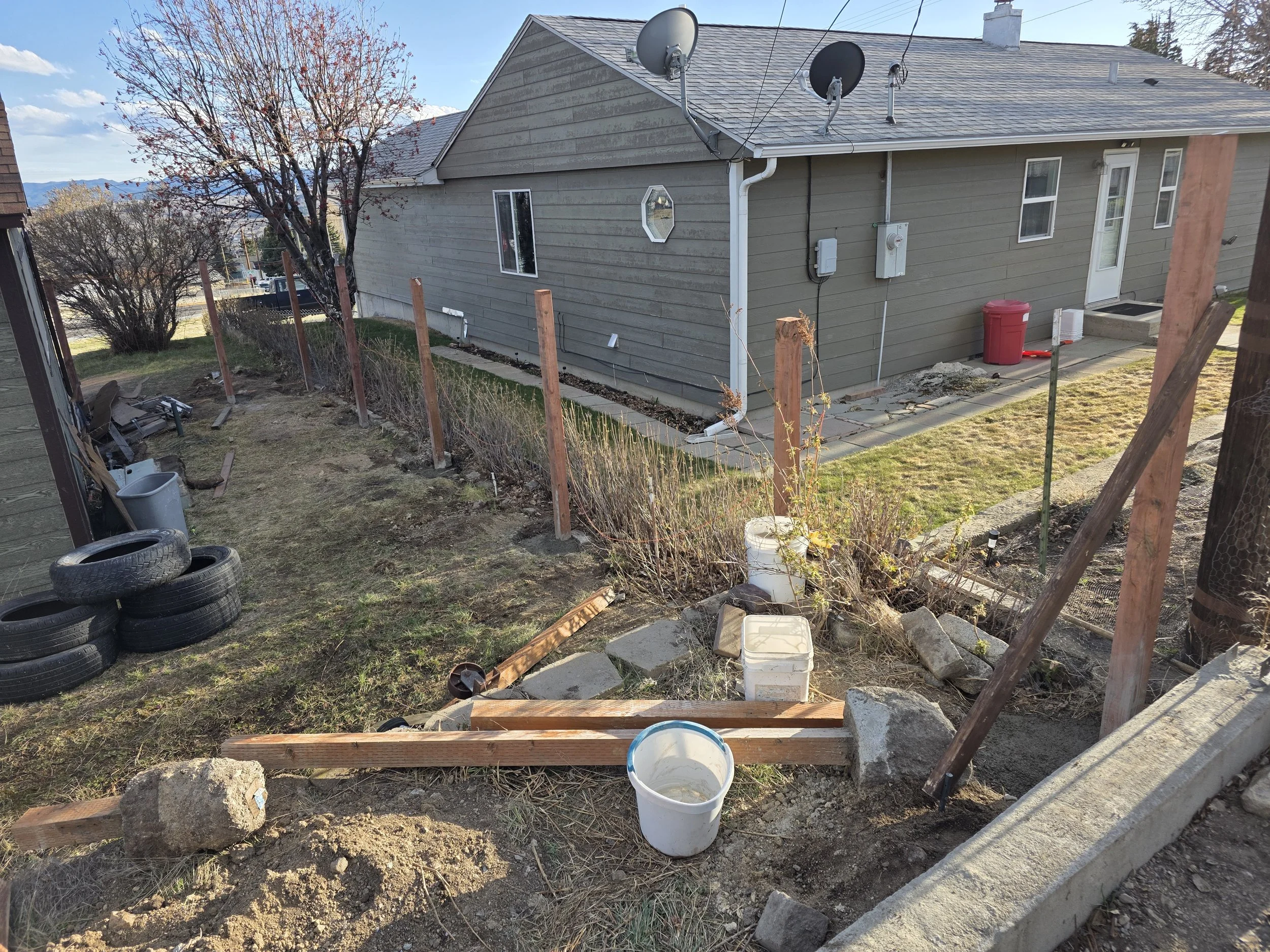 Old fence torn out and new post holes dug for a cedar privacy fence in Walkerville, Montana