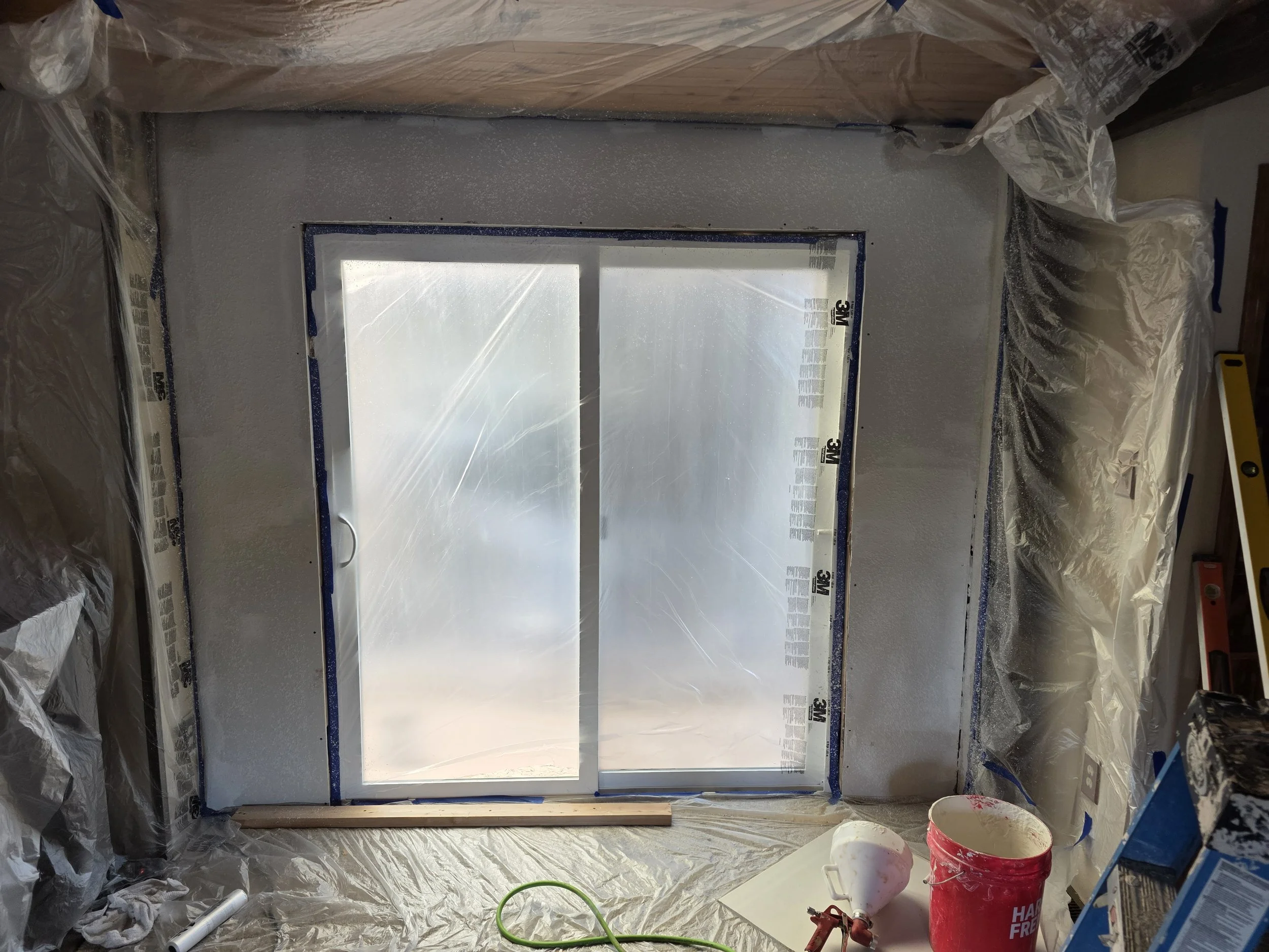 Sliding glass door set in the new wall, wrapped in plastic for finish work, Whitehall, Montana
