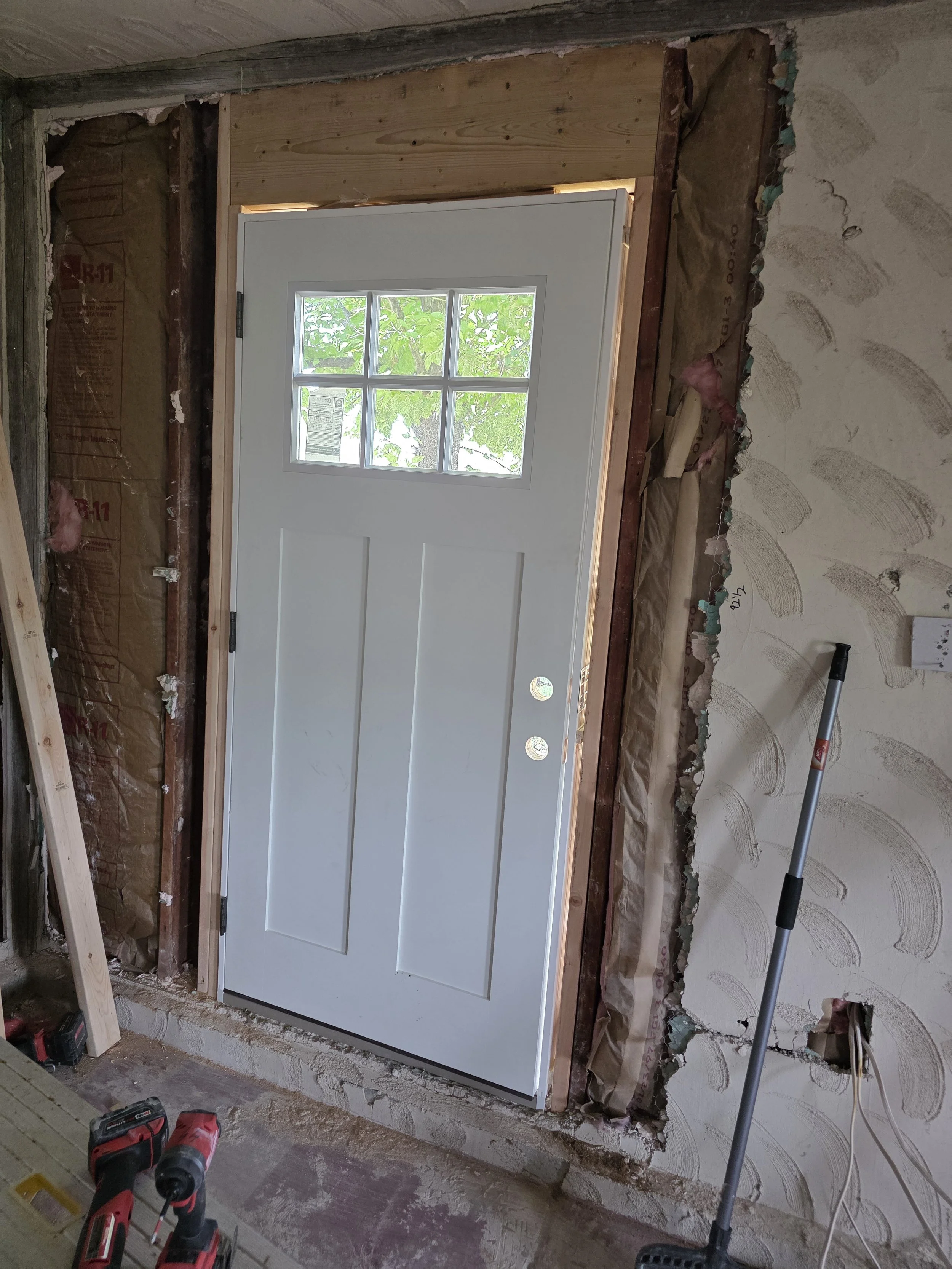 New entry door set in the rough opening before trim, Cardwell, Montana bunkhouse remodel