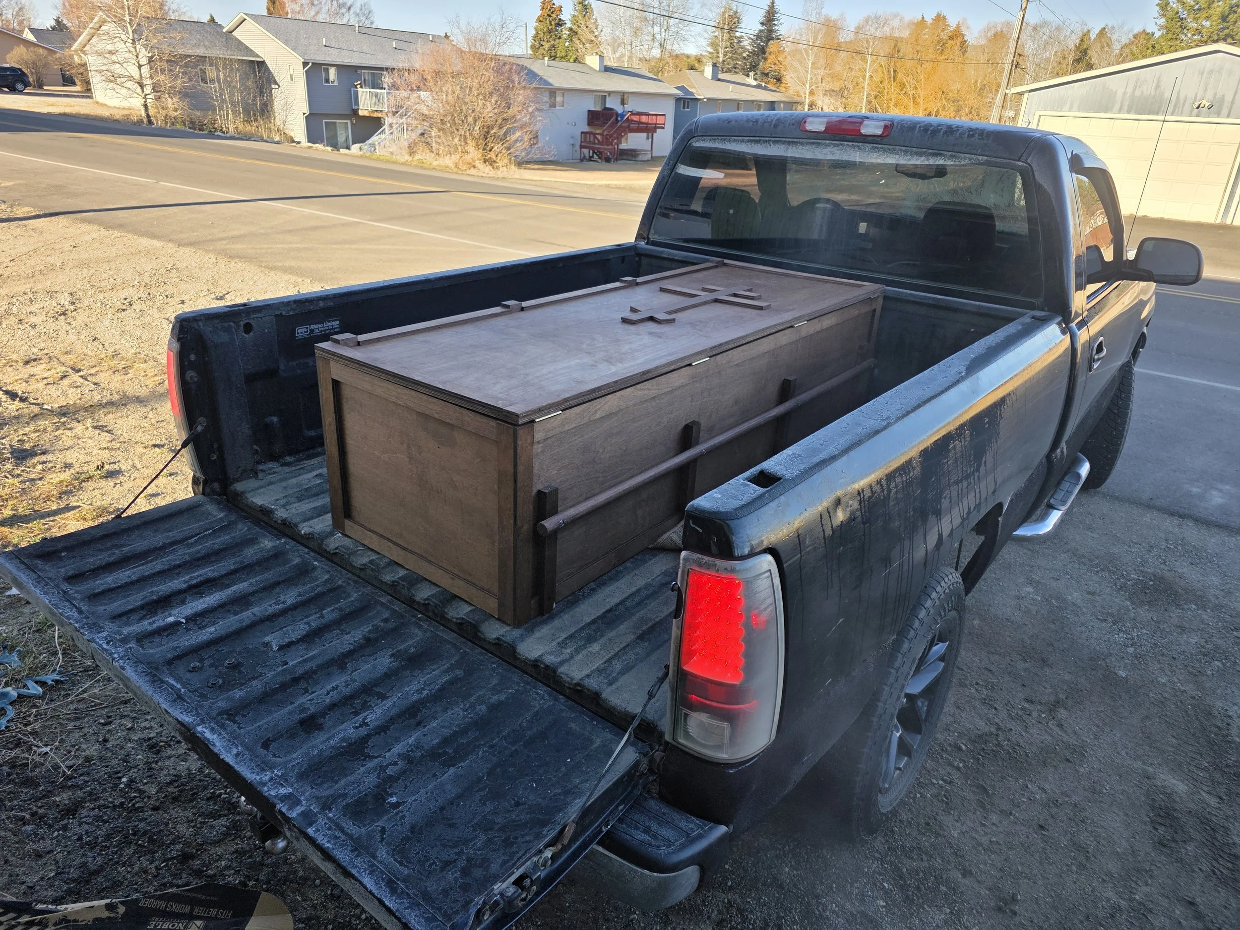Finished handmade casket with a cross on the lid, loaded for delivery, Butte, Montana