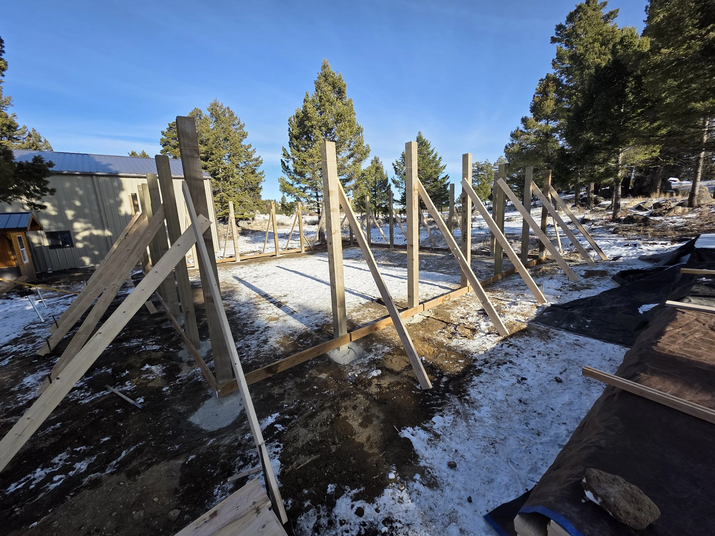 Pole barn posts set and braced in the snow, Whitehall, Montana