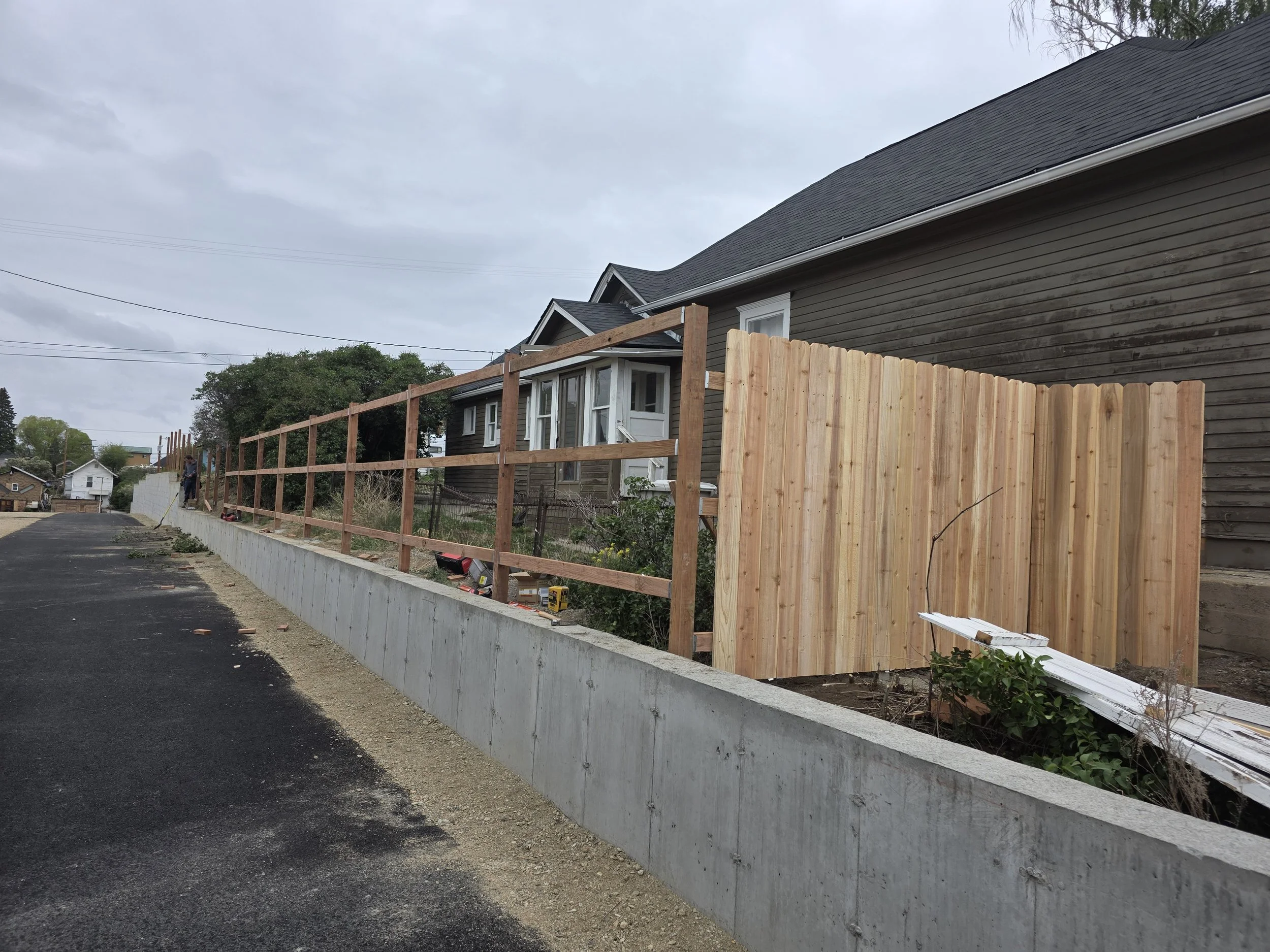 Rails up and cedar pickets going on the retaining wall fence, Uptown Butte, Montana