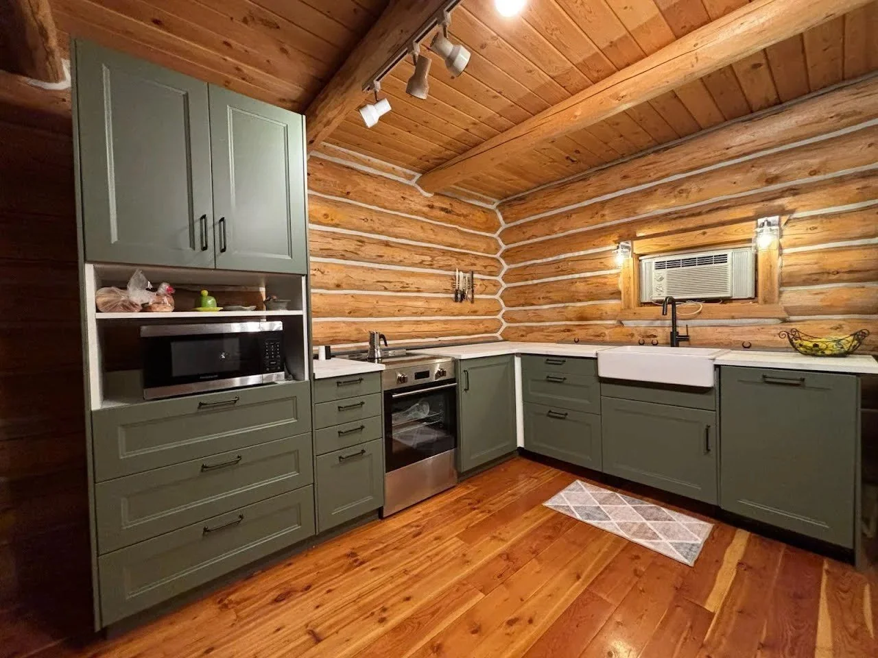 Finished log-home kitchen with new green cabinets and hardwood floor, southwest Montana