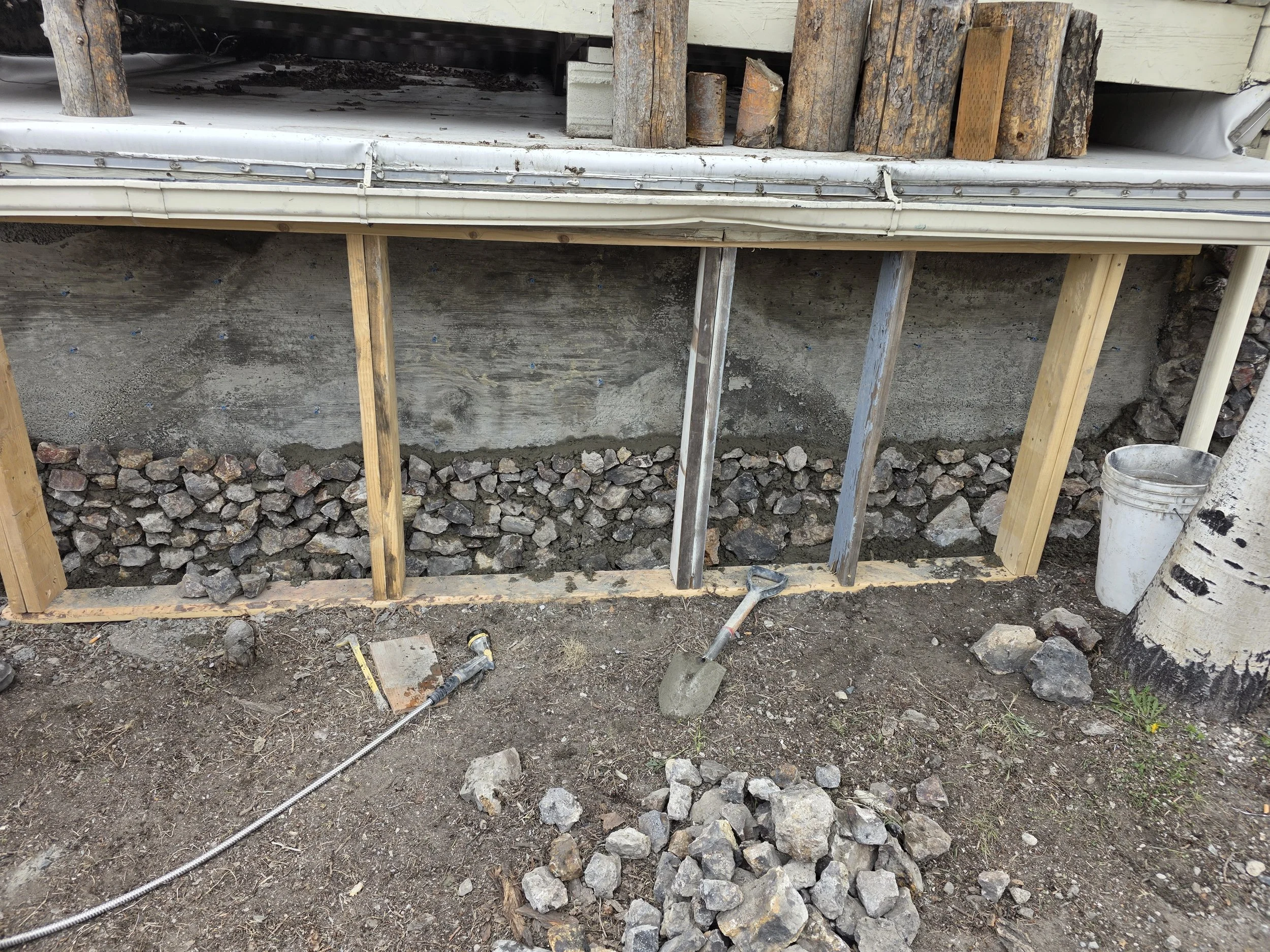 New concrete wall poured with the first courses of original stone reset, Butte, Montana