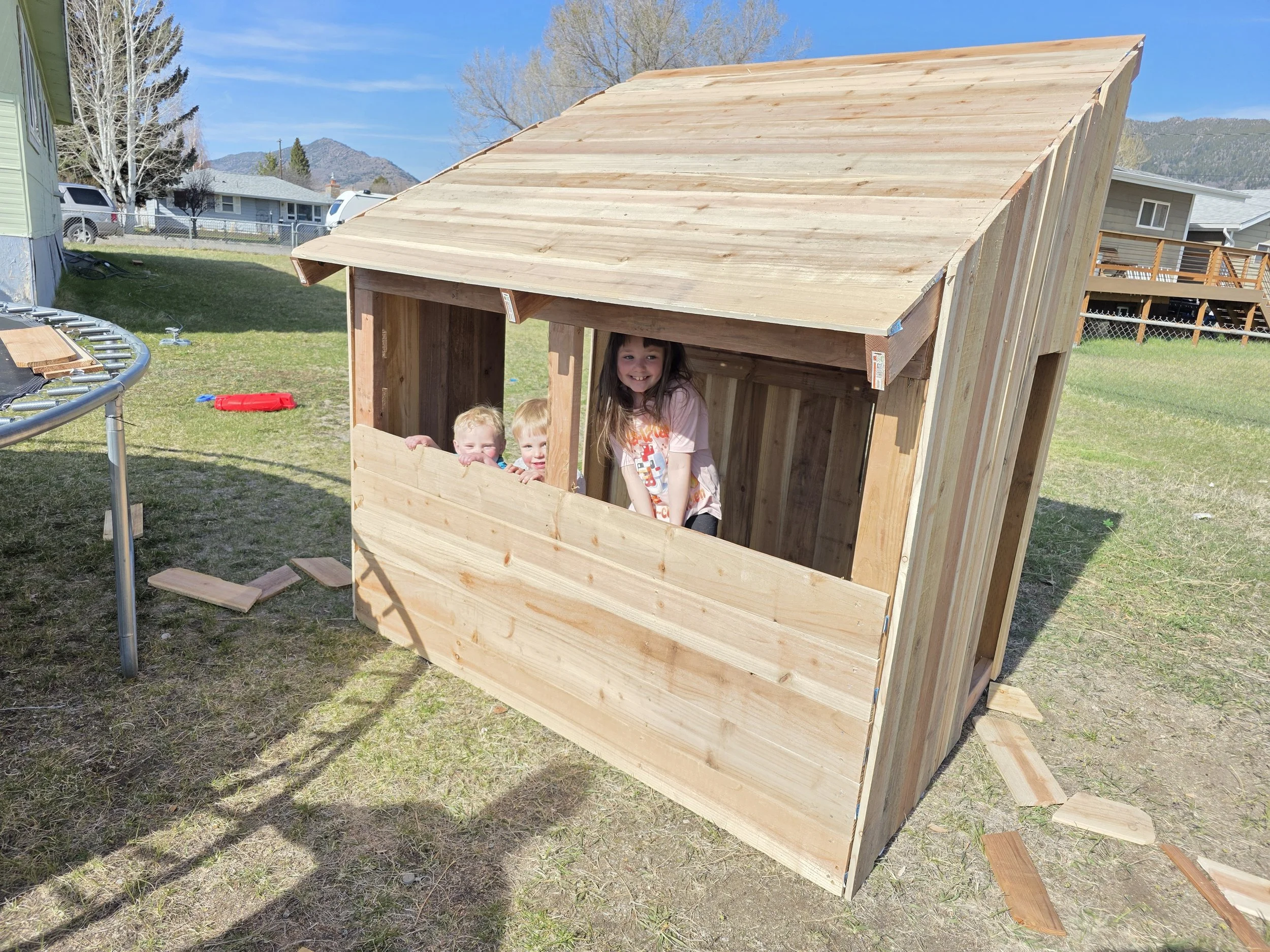 Finished cedar playhouse with kids at the window, near Belgrade, Montana
