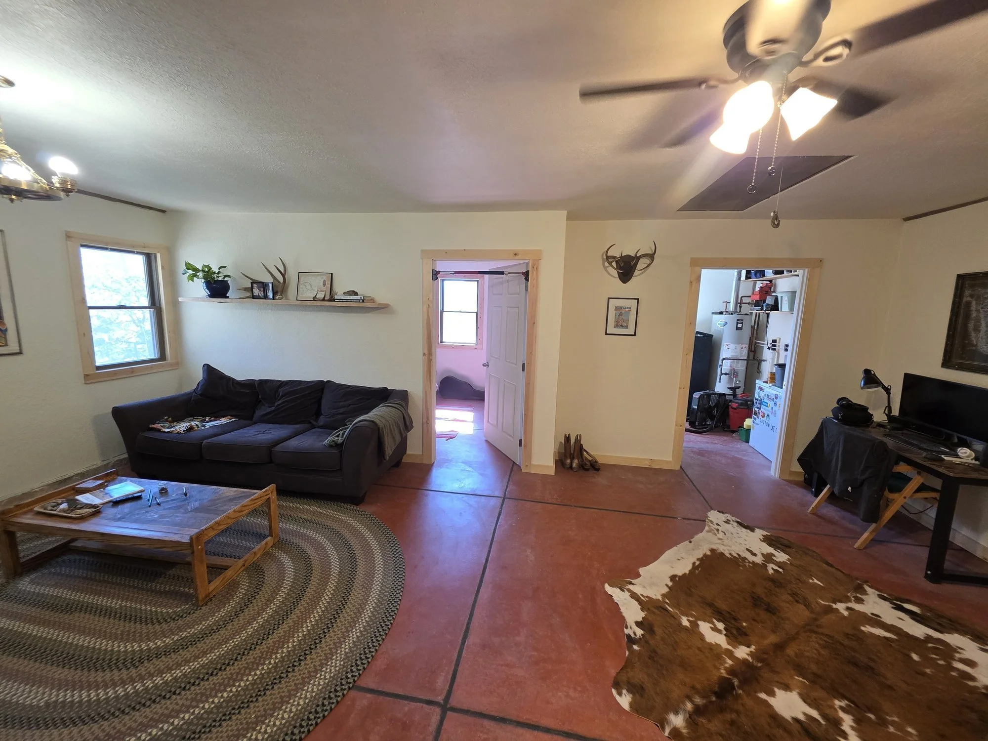 Renovated bunkhouse living room with stained concrete floor and area rugs, Cardwell, MT