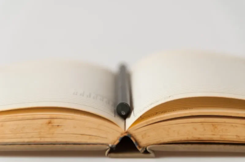 Open book with blank pages and a black pen resting on top.