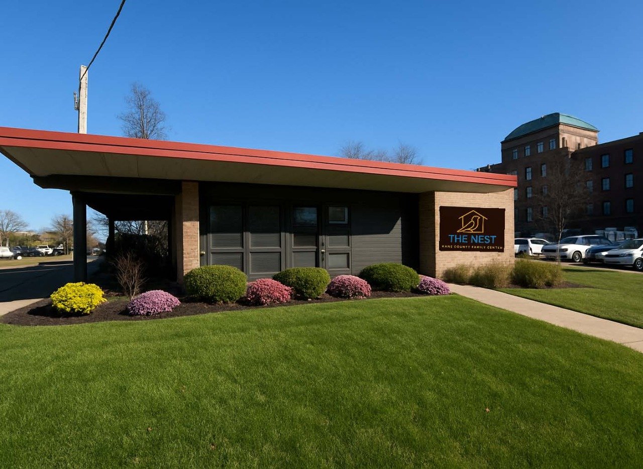 Building labeled 'The Nest - Kane County Family Center' with a landscaped lawn and flower bed in front.