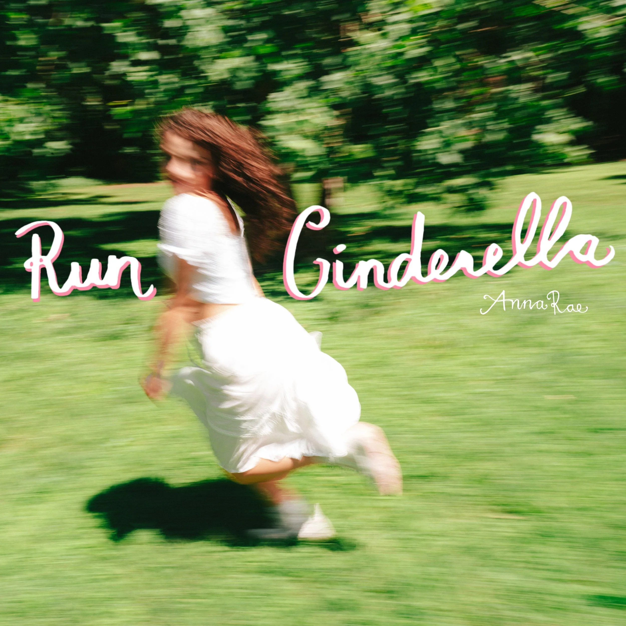 A blurred image of a woman with long hair wearing a white dress outdoors on a bright day, with green trees and grass in the background, and pink text overlay.
