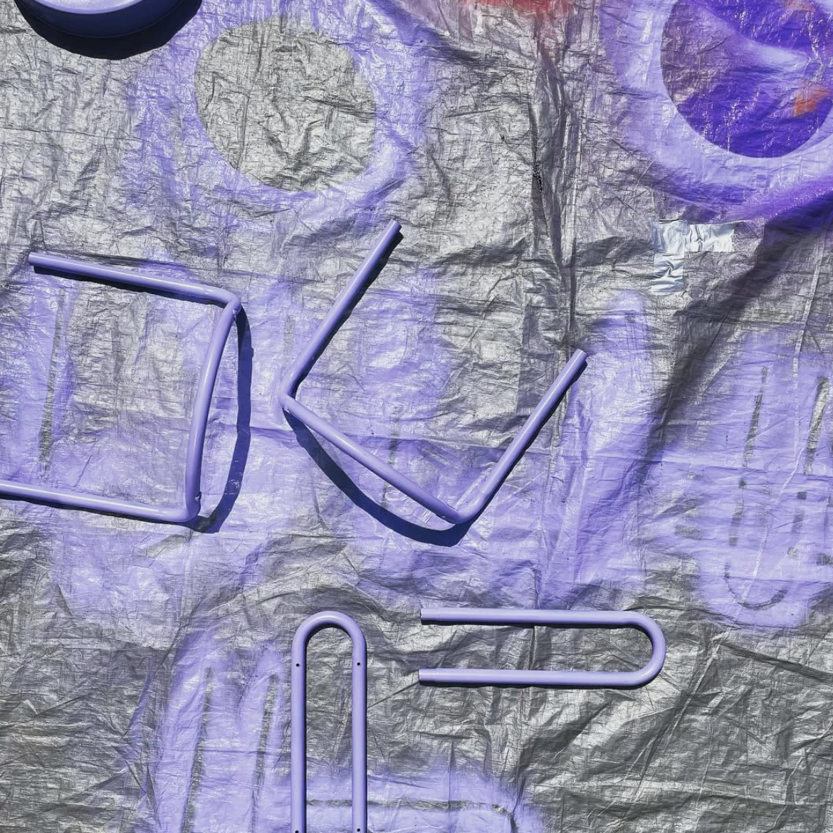 Six purple plastic straws placed on crinkled metallic paper, some bent at angles, with purple lighting casting a glow.