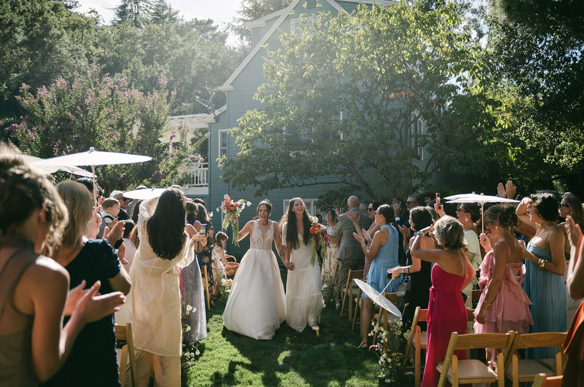 People celebrating outdoor wedding with a bride and groom dancing among guests in a garden setting.