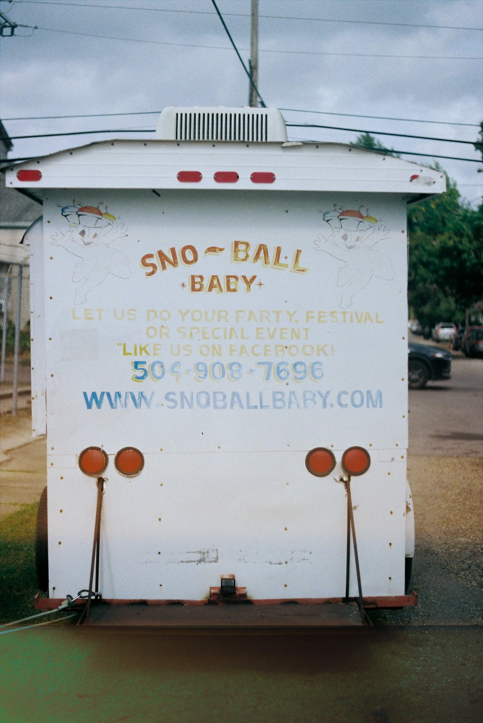 The back of a snoball trailer with cartoon characters and business contact information.