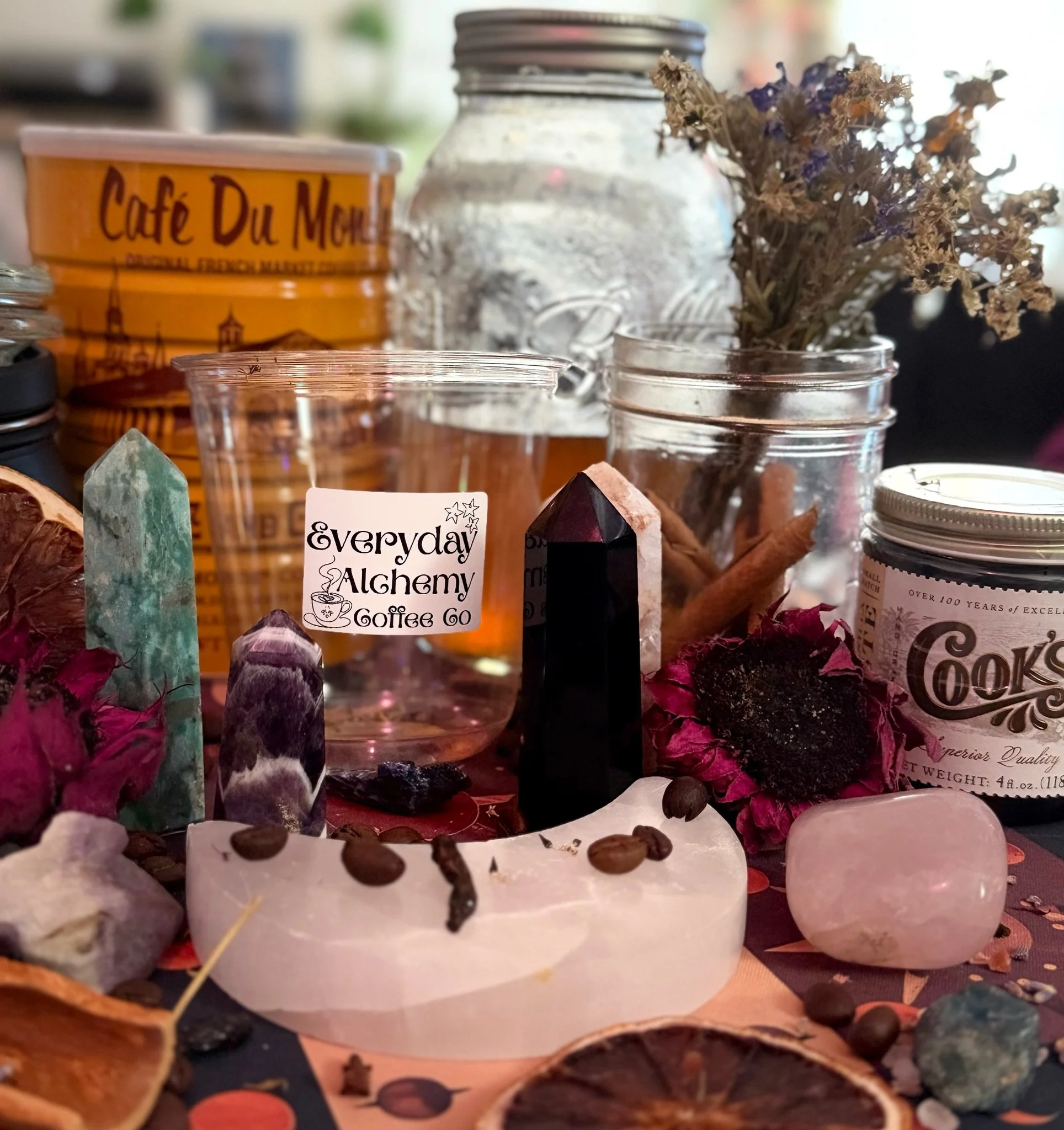 Everyday Alchemy Coffee cup surrounded by crystals, glass jars, dried flowers and a Café du Monde coffee tin.