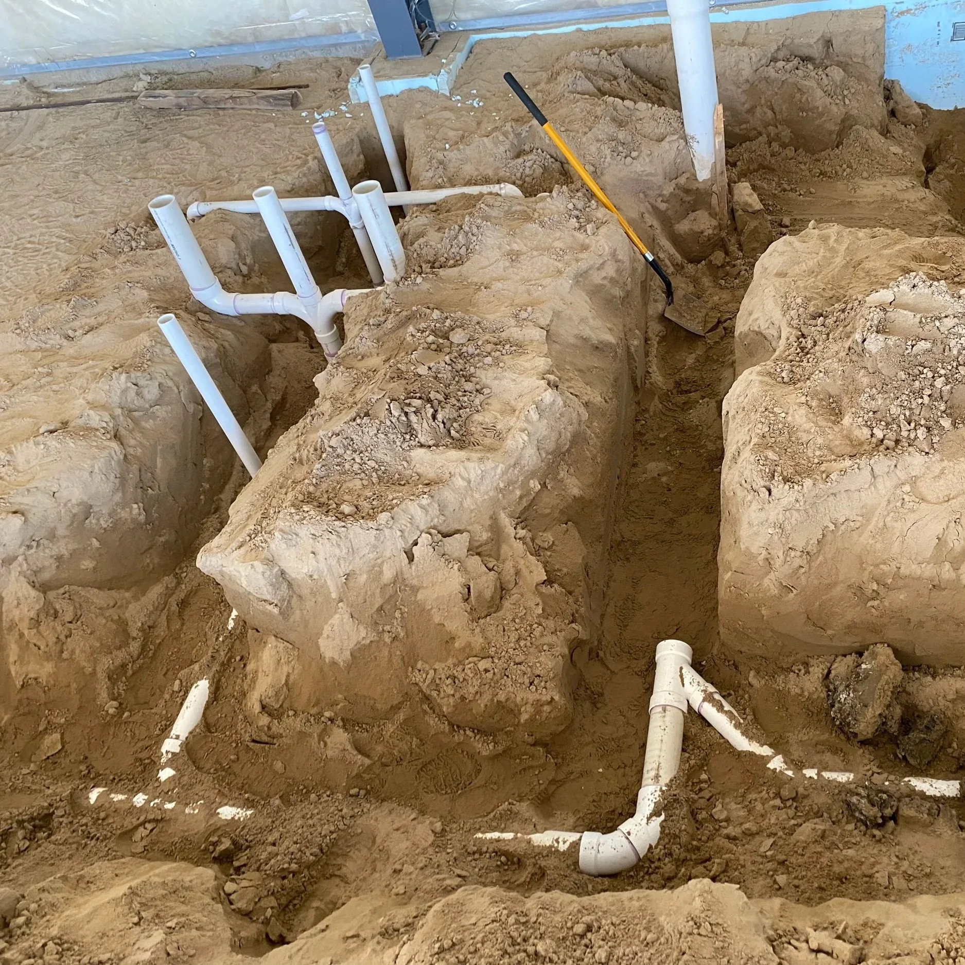 Underground plumbing pipes in a trench with dirt and soil.