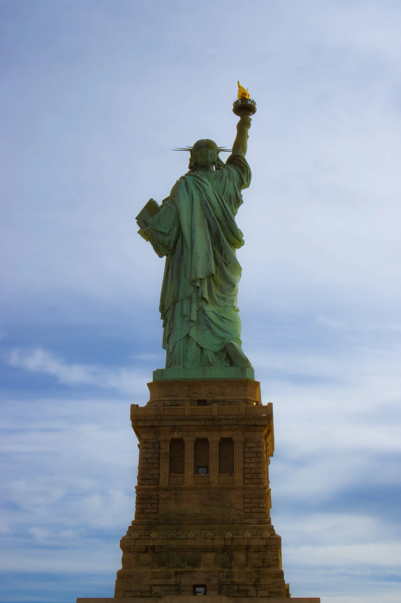 The Statue of Liberty viewed from below against a cloudy sky.