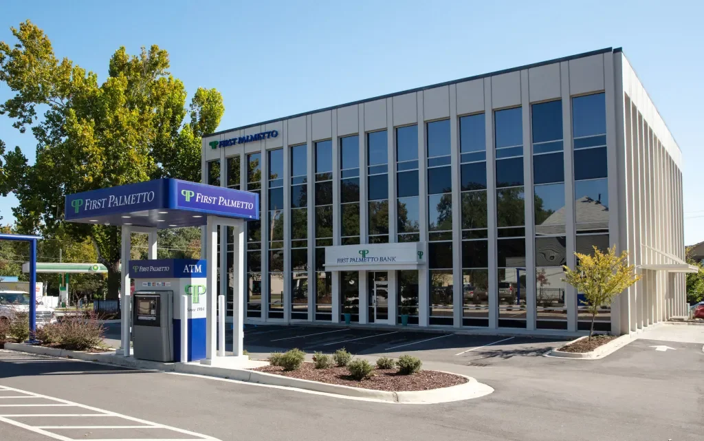 Exterior of First Palmetto Bank building with bank sign, ATM, and parking lot on a sunny day.